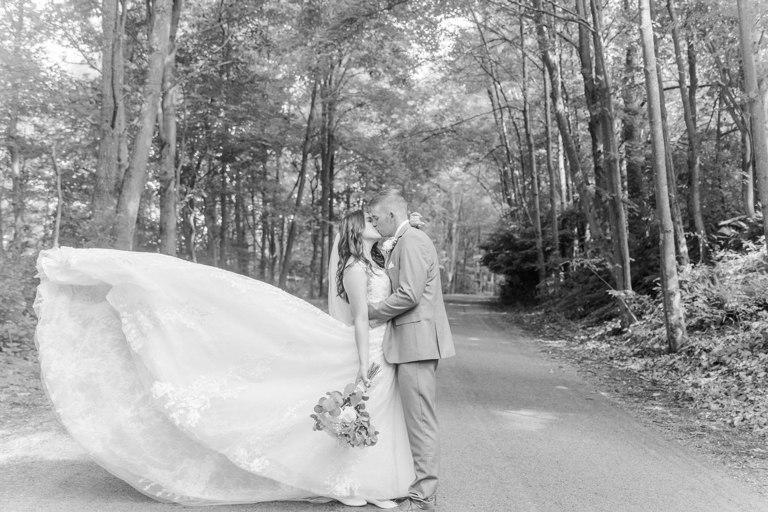 Black and white wedding photos captured on a tree-lined path.
