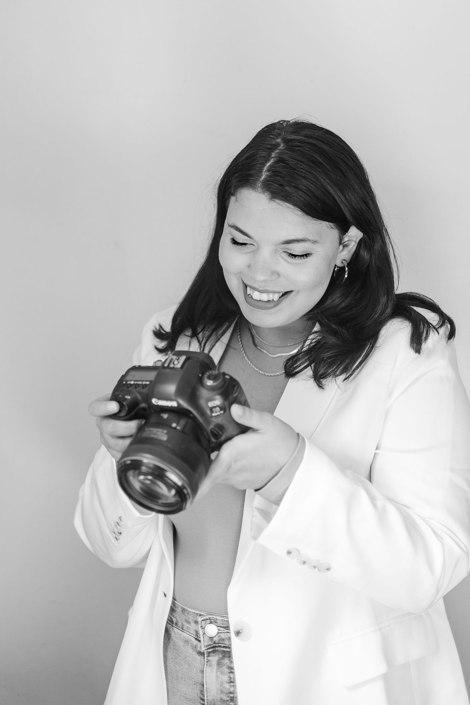 A series of black and white photos showing someone in a white shirt posing with a camera against a light background.