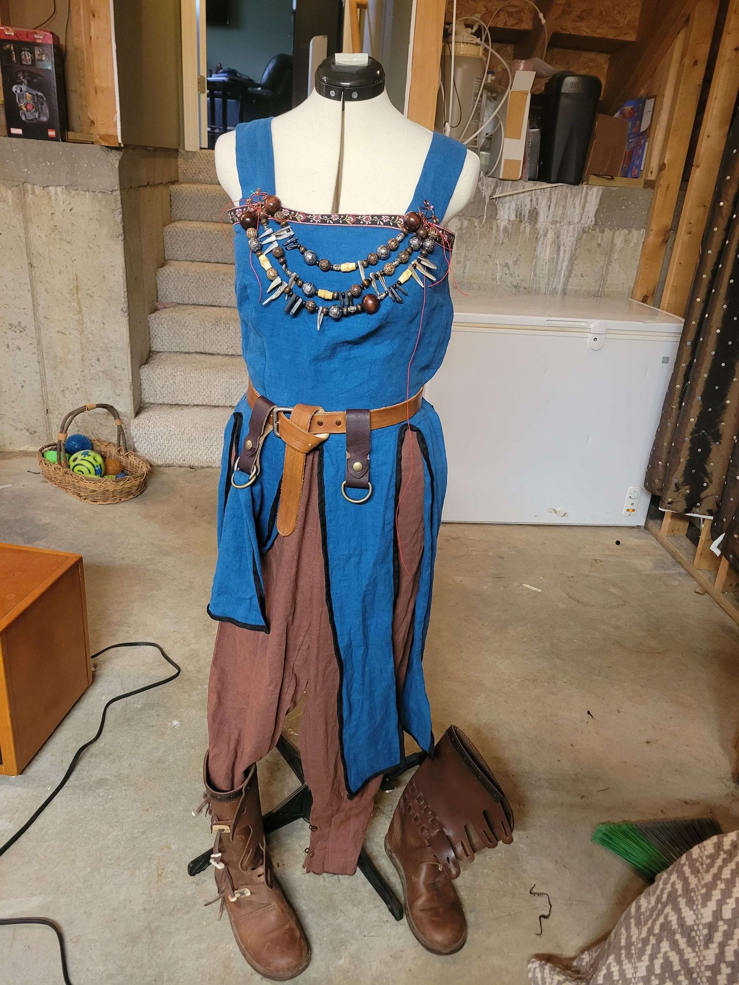 Cosplay costume displayed on mannequin featuring blue overalls, leather accessories, spikes, and brown combat boots.