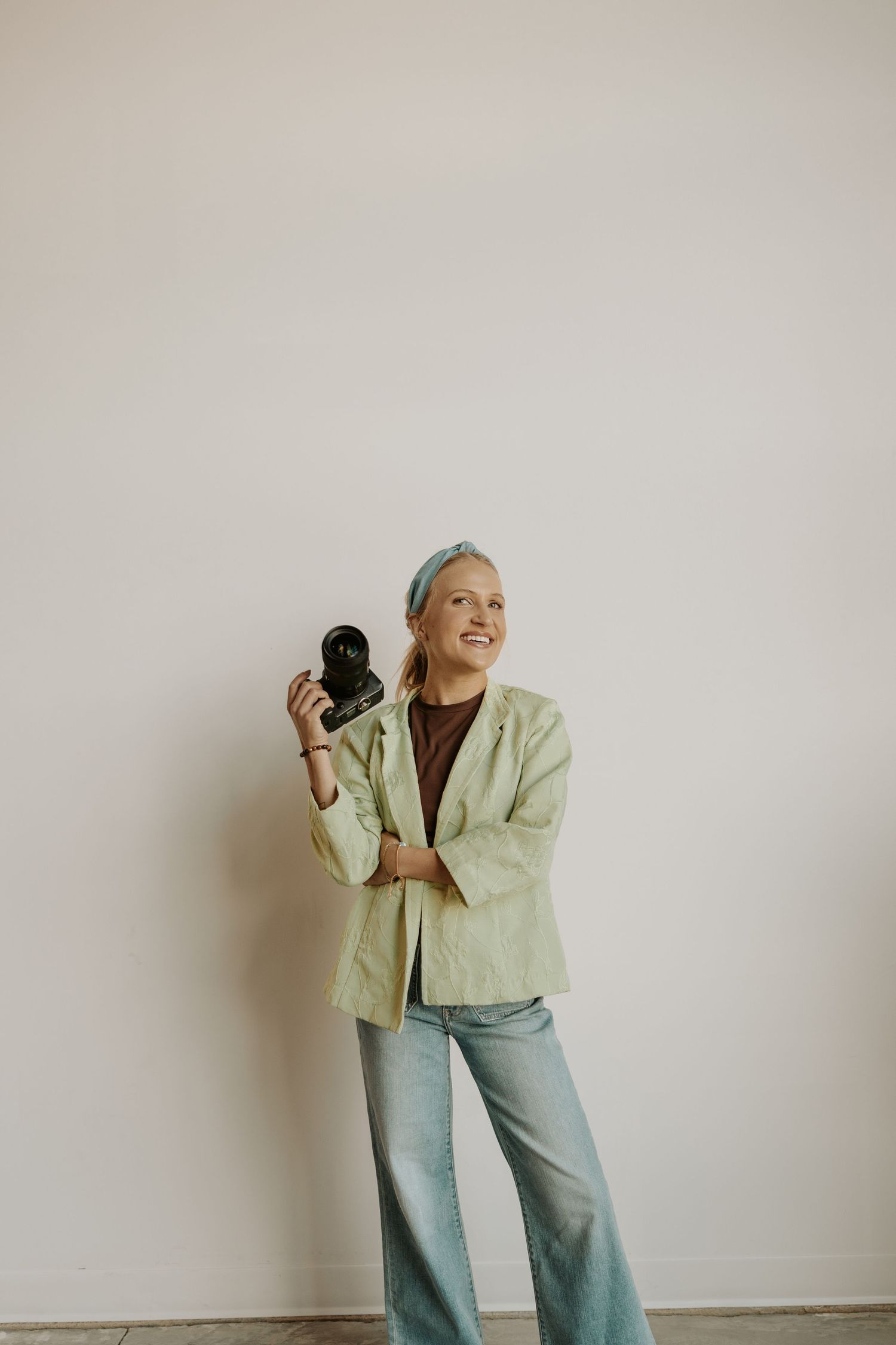 A person wearing a mint green jacket and light denim jeans poses playfully against a white wall in multiple shots.