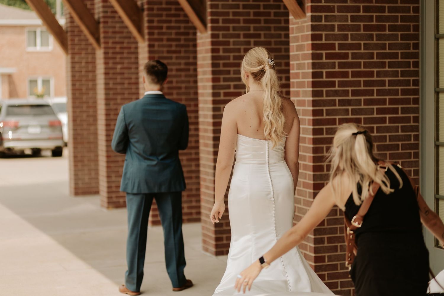 Bride and groom walk together under brick archways at an elegant outdoor venue during their wedding celebration.