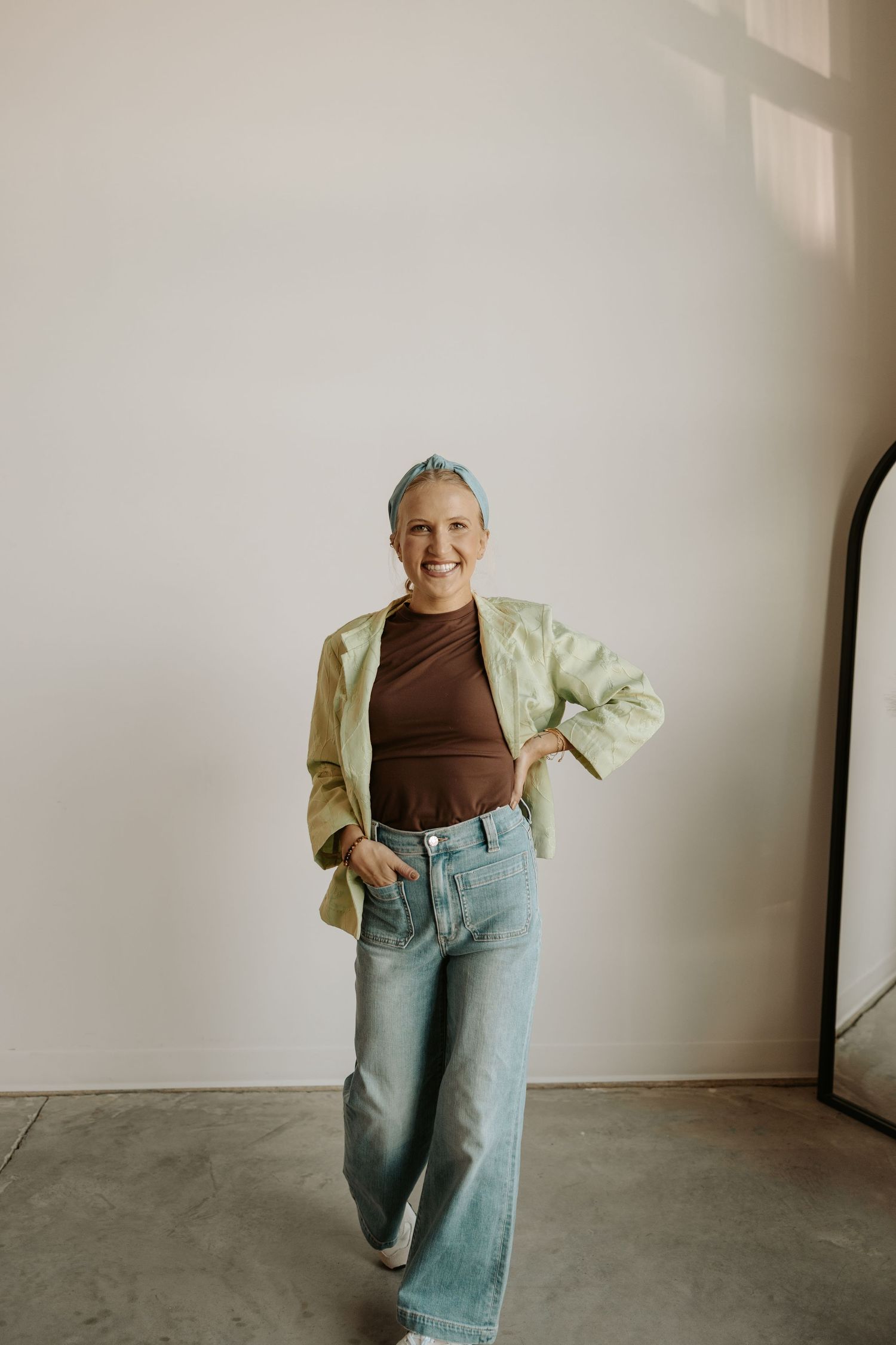 nebraska wedding and lifestyle photographer in a studio wearing jeans, brown shirt, green jacket. studio brand photographer session