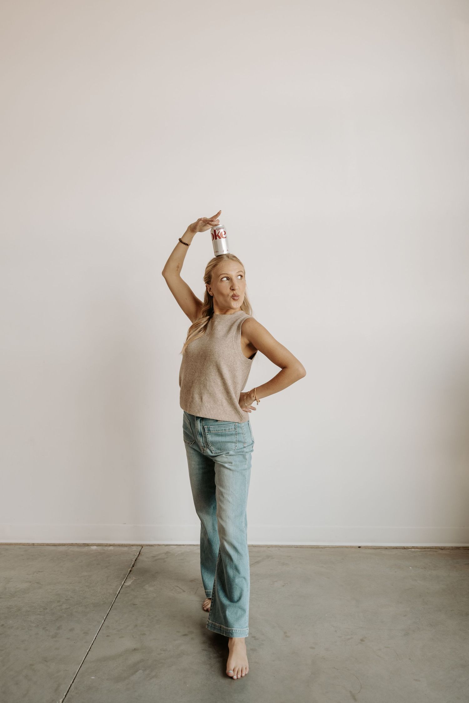 A sequence of dance movements captured in four frames showing a person in beige top and blue pants against a white wall.