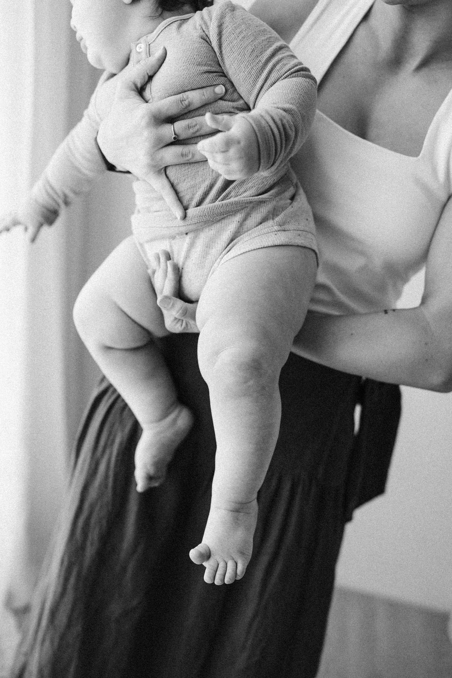 Black and white photograph shows sequence of adult arms holding and supporting a baby in repeated poses.