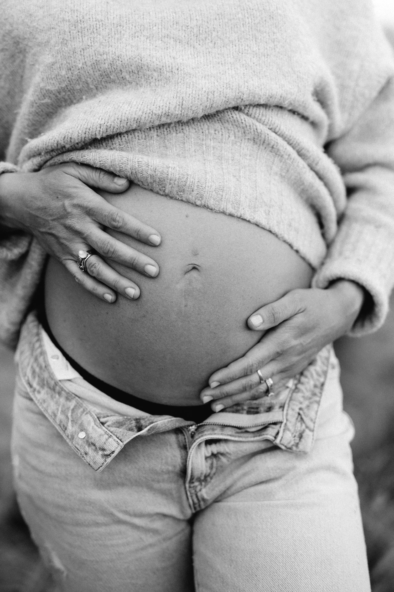 A black and white photo series showing the progression of a pregnant belly with hands gently resting on it.