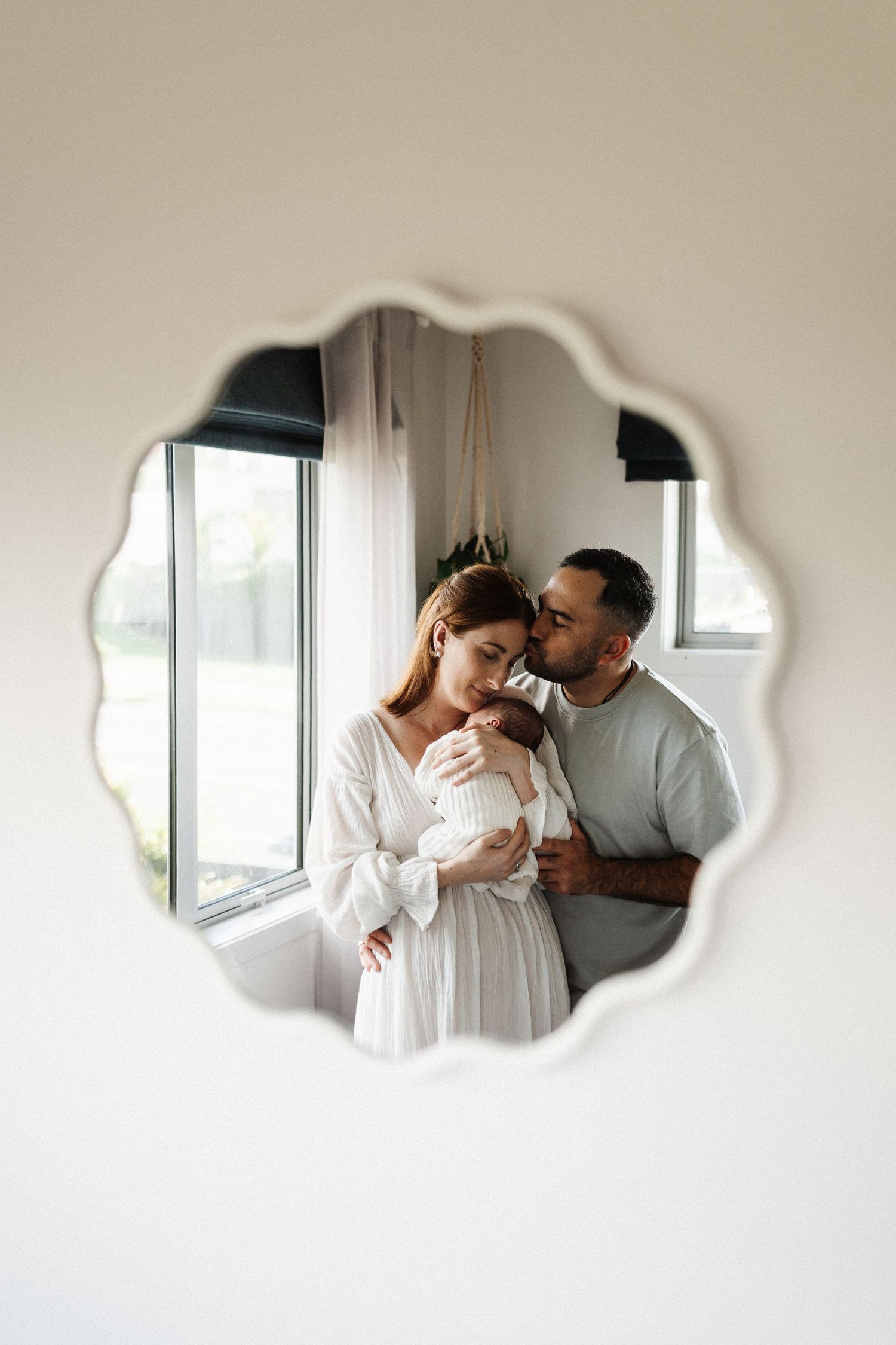 Romantic couple sharing tender moments in minimalist setting with white walls and natural light.