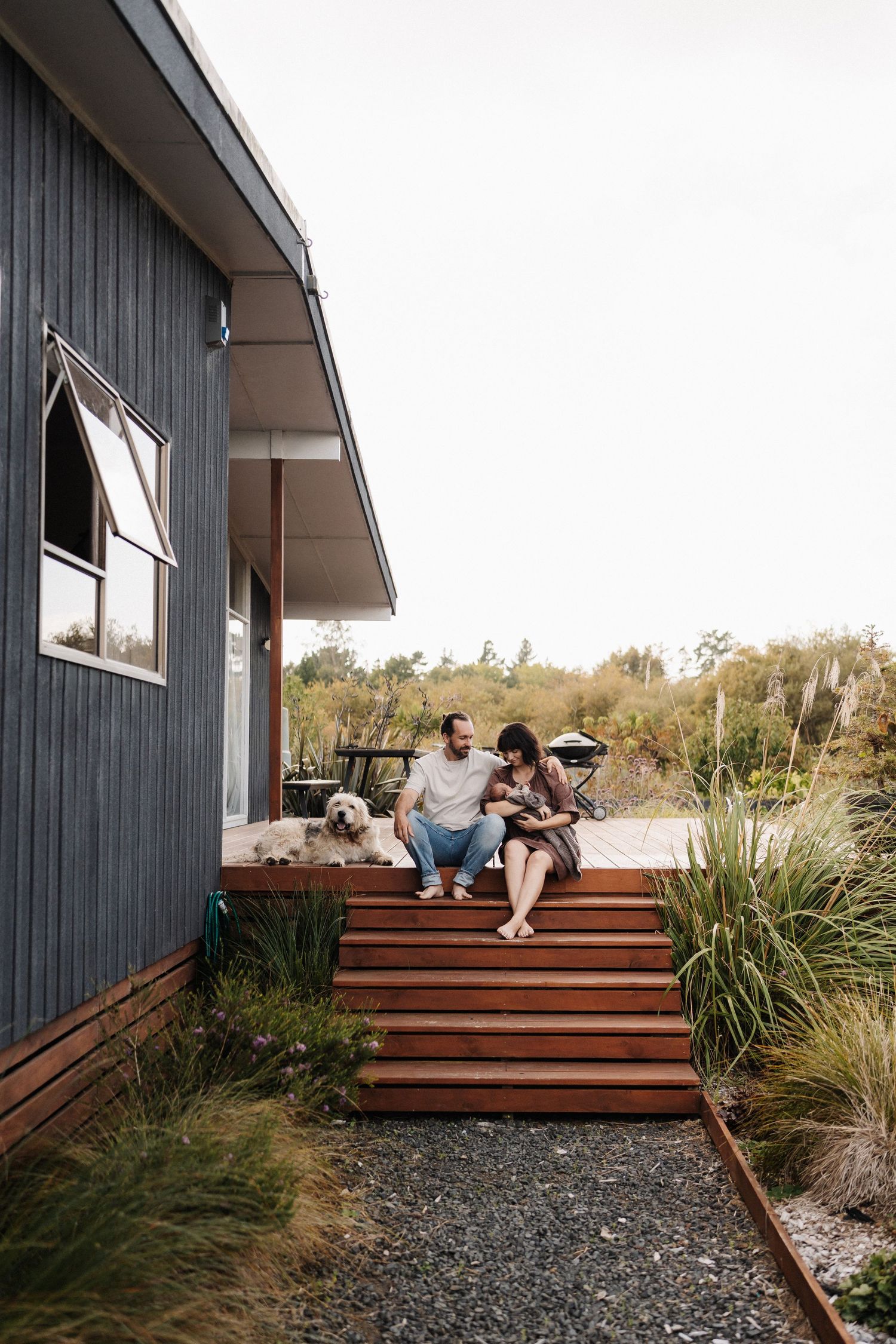 Modern wooden deck with coastal landscaping features ornamental grasses and gravel ground cover at sunset.