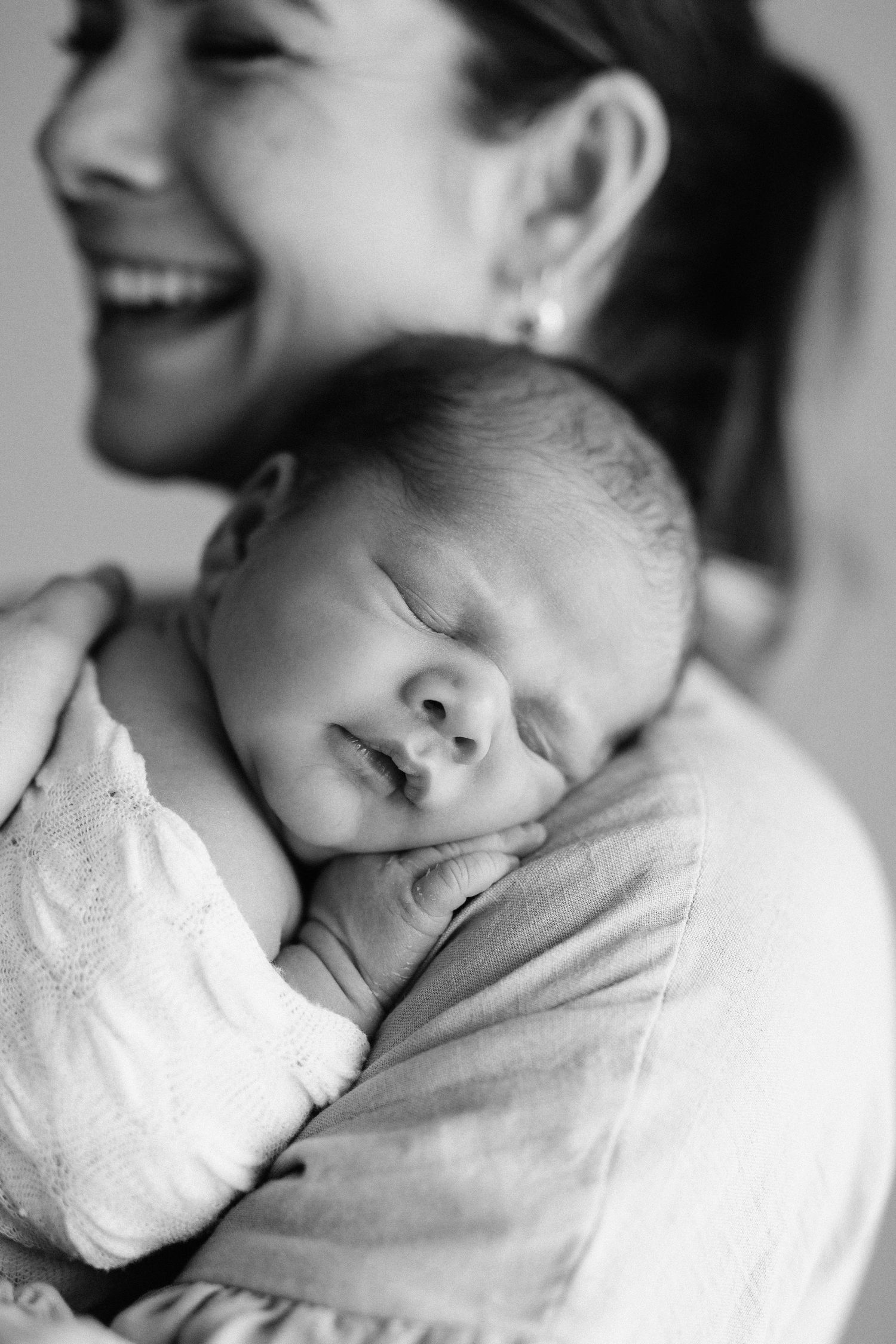 A touching black and white photo series shows tender moments between a sleeping newborn baby and a caregiver.