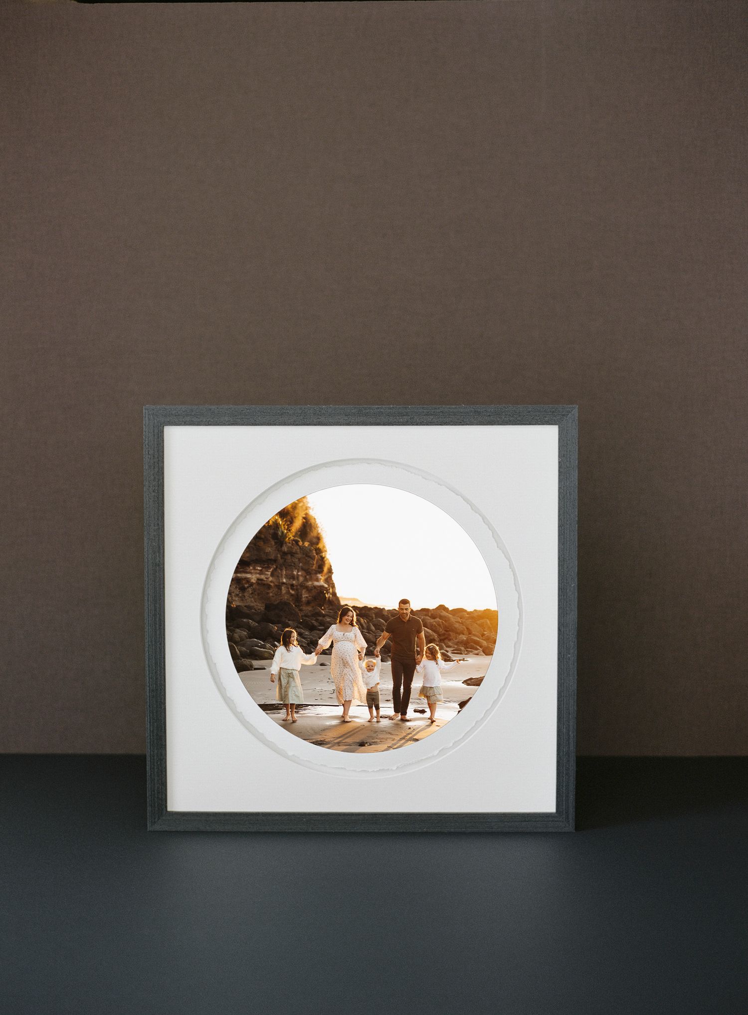 Four sequential images showing a panoramic photograph being progressively framed in white matting on a dark surface.