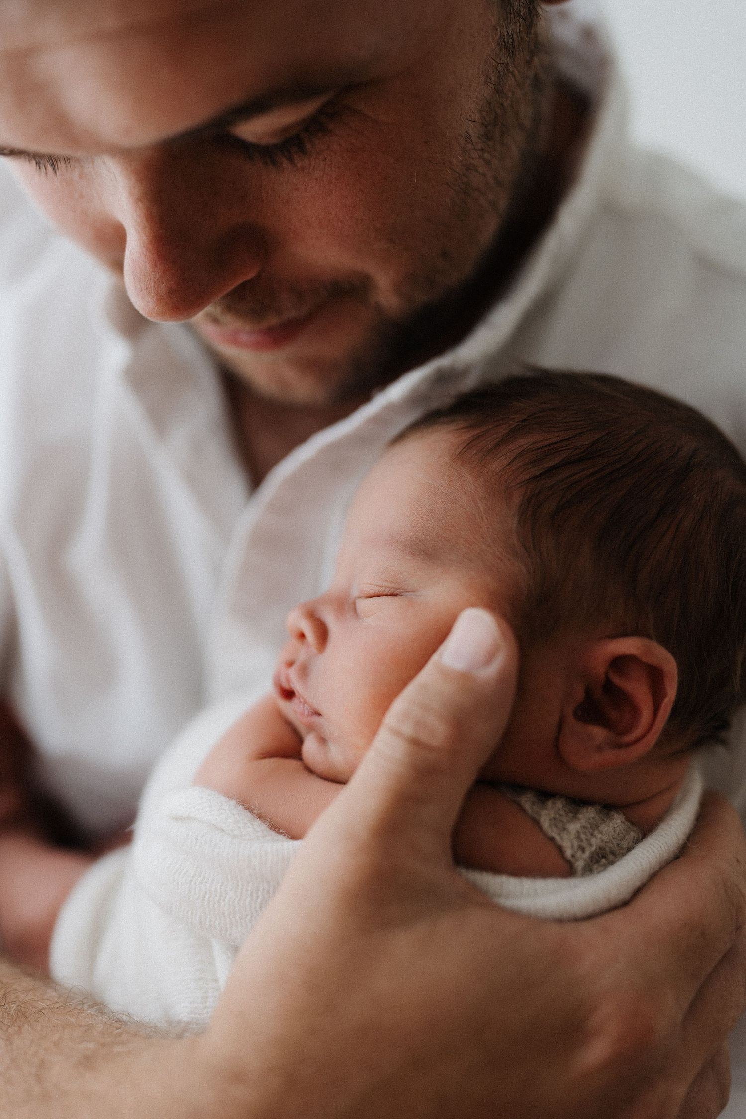 A tender moment between a parent and sleeping newborn baby shown in multiple intimate black and white photos.