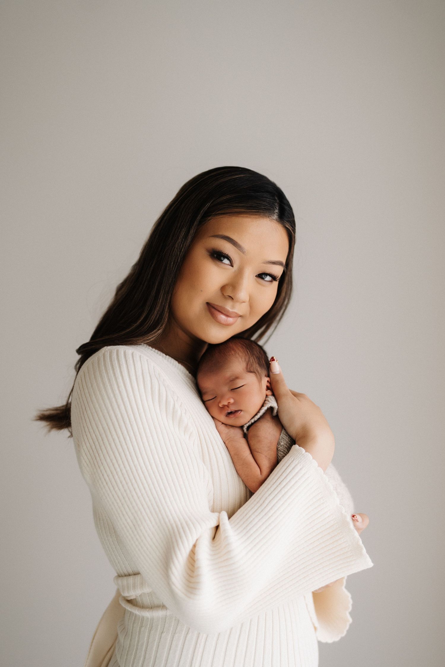 A tender moment captured in a series of photos showing a parent in a white sweater holding and bonding with a newborn baby.