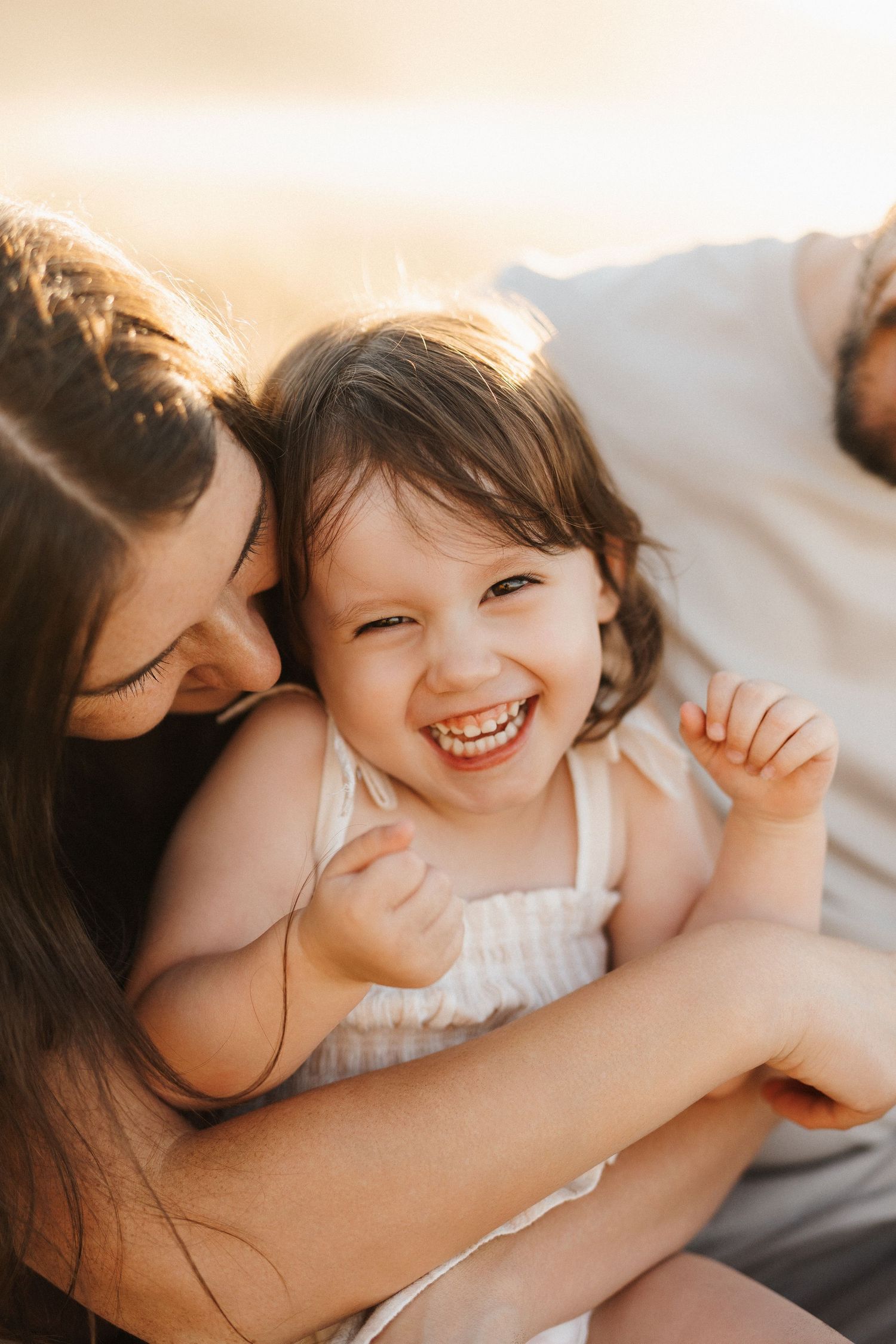 A heartwarming candid moment of parent and child sharing joyful laughter while cuddling together on a couch.