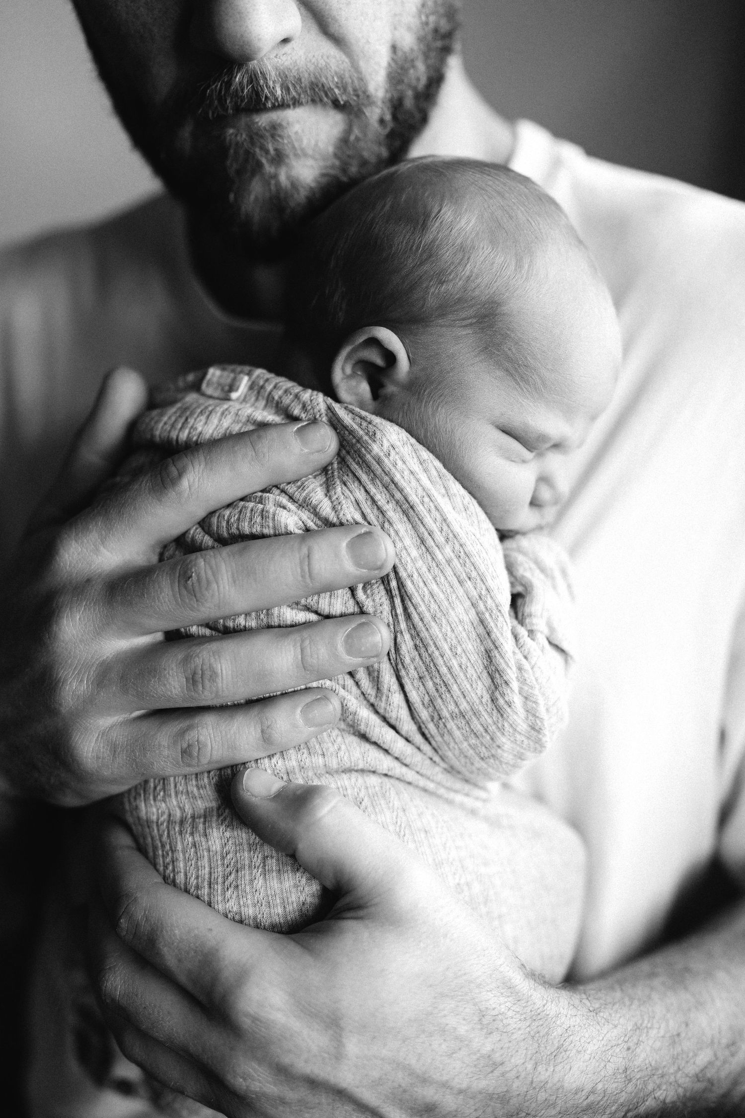 A series of black and white images showing a baby sleeping comfortably cradled in caring arms.