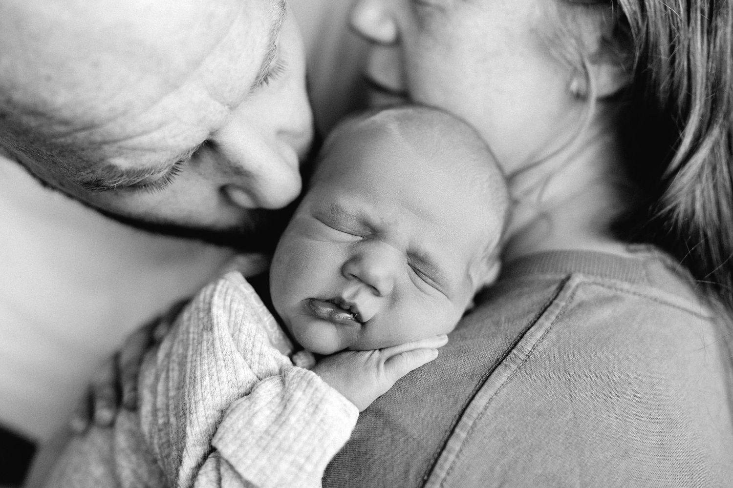 A tender moment captured in black and white of a sleeping baby surrounded by soft blankets.