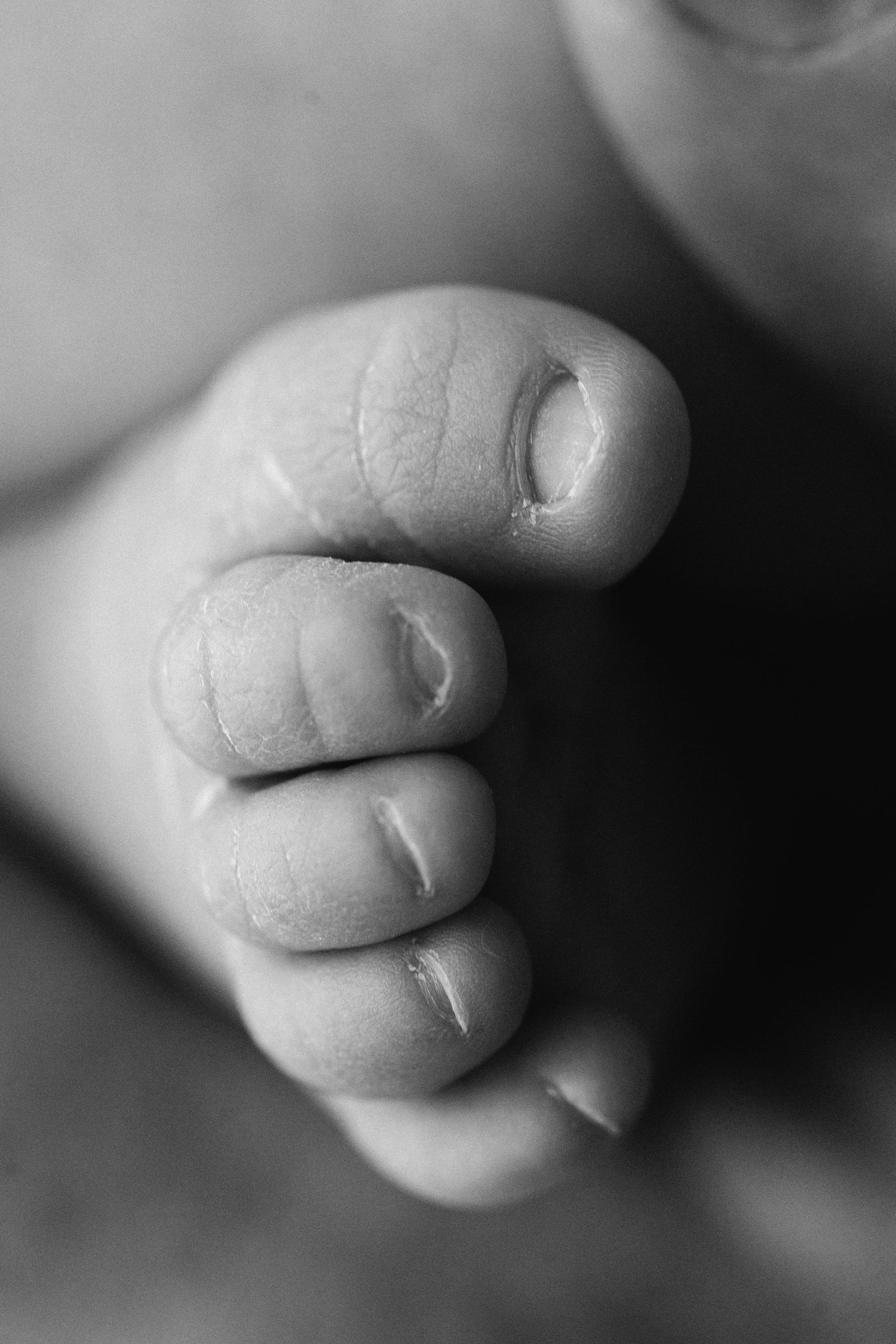 Close-up black and white macro photography captures soft baby toes in shallow depth of field.
