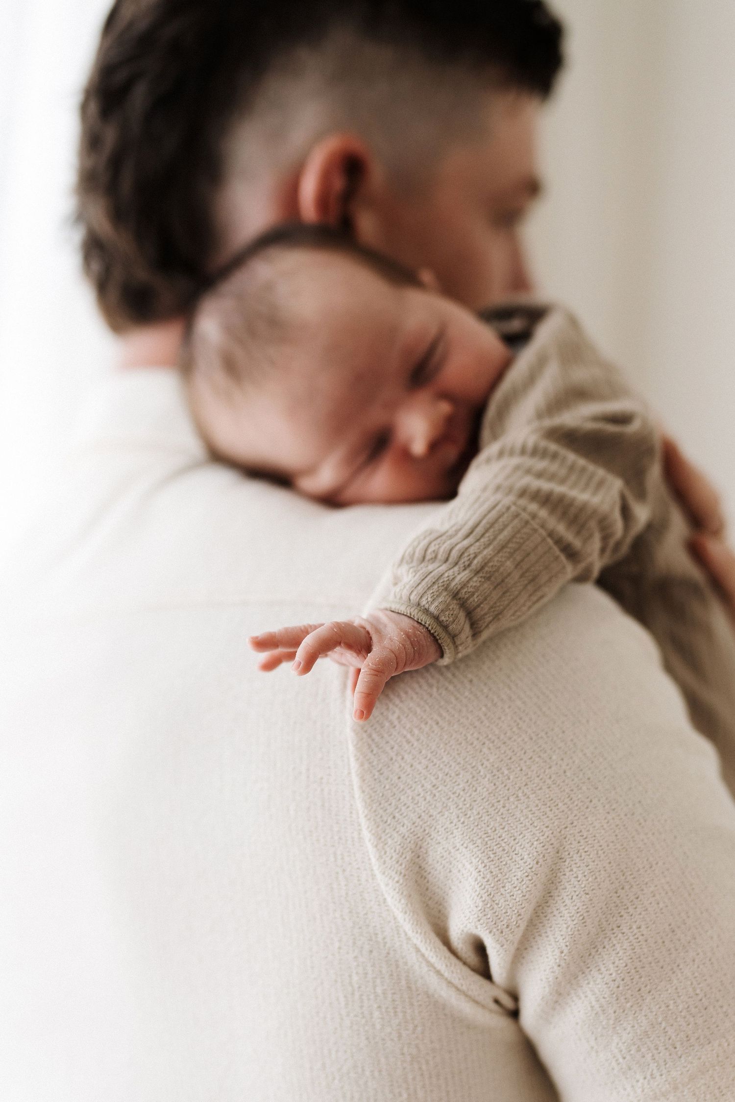 A person in a beige knit sweater lays down and rests peacefully against a soft white surface.