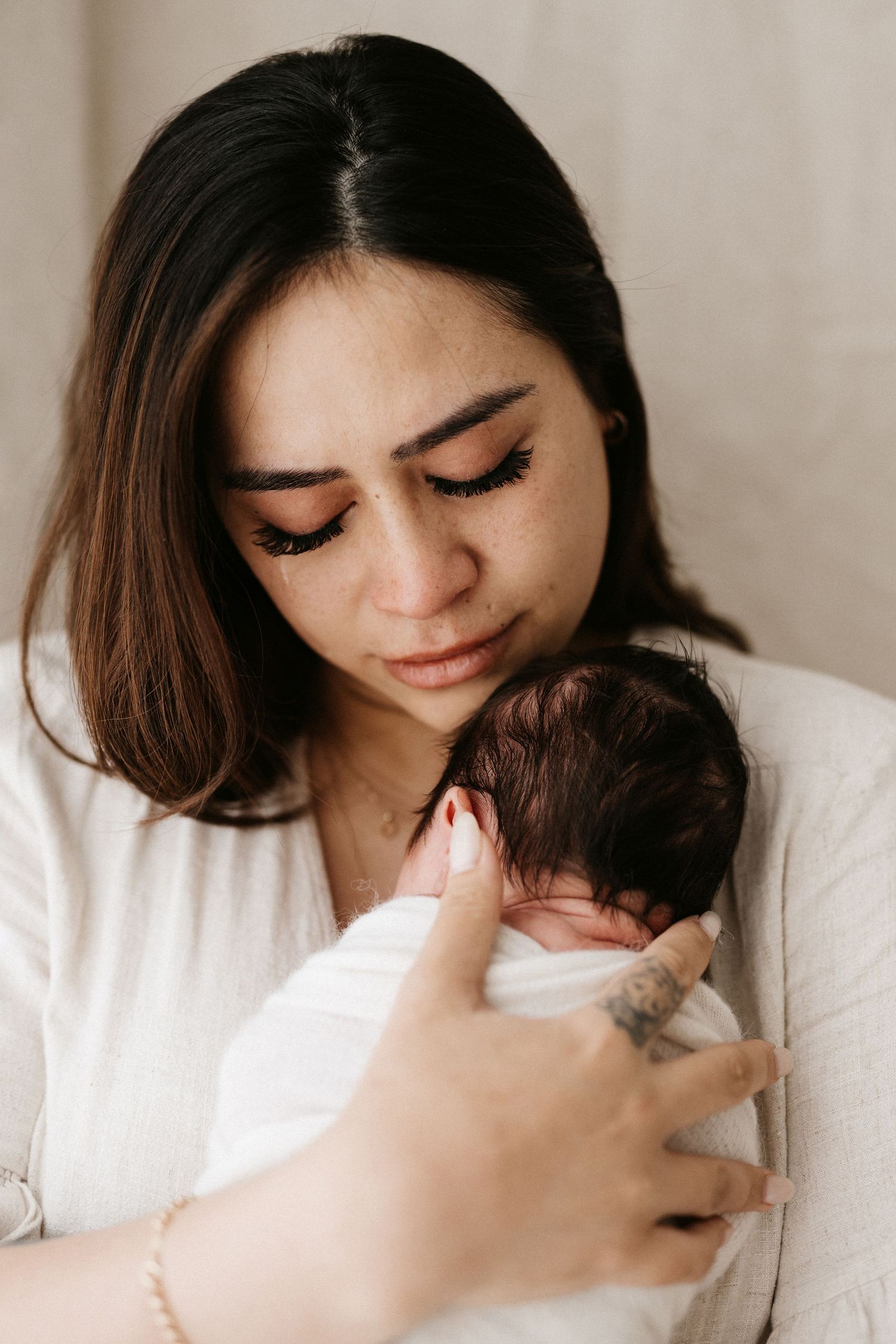 Three serene images show tender embraces between a mother and newborn baby in white clothing.