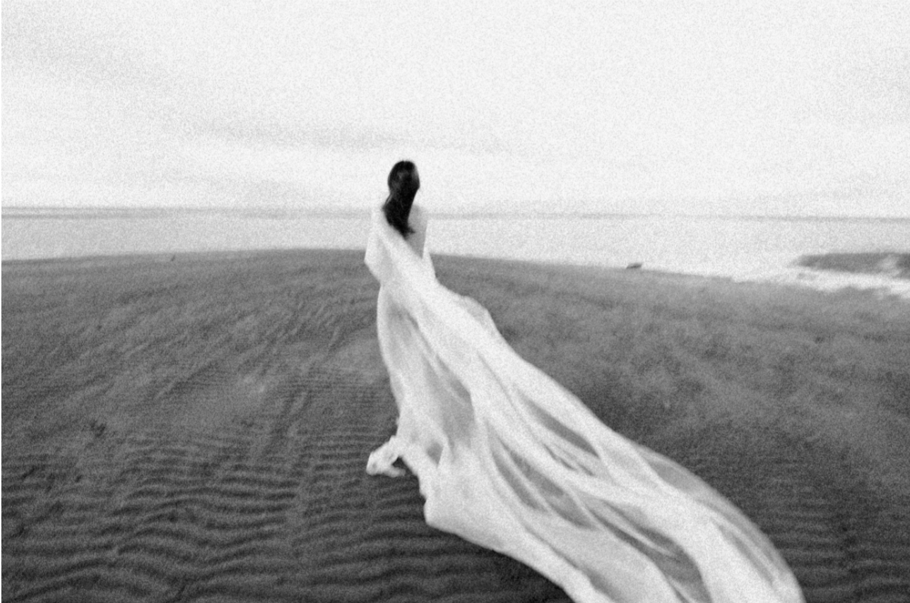 Mariée marchant sur une plage avec un long voile