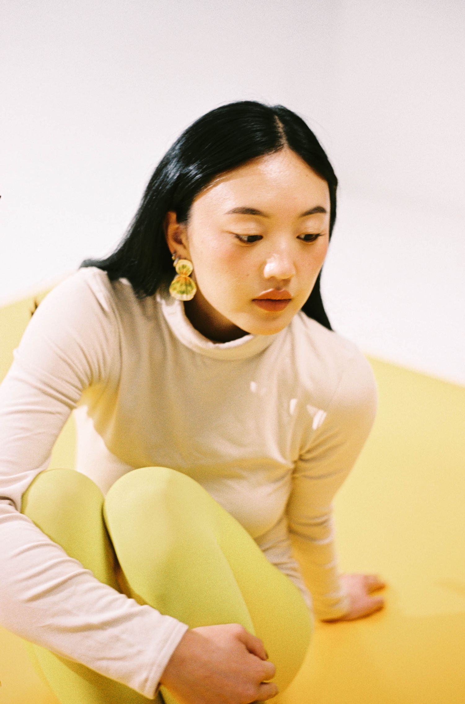 35mm film editorial portrait in Westchester, NY: woman in a cream turtleneck and yellow statement earrings