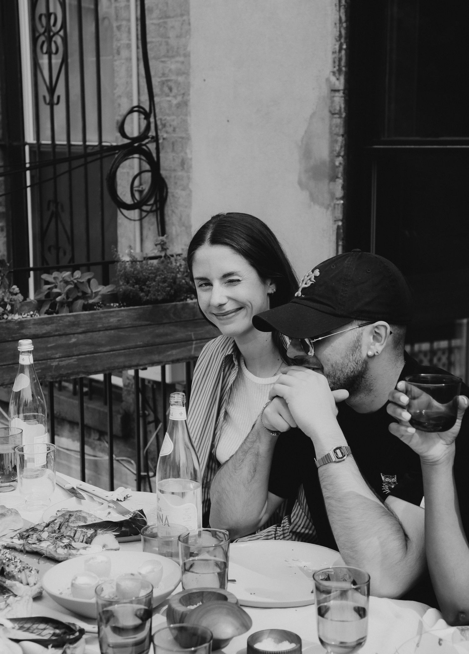 Black and white photo of two guests smiling at an outdoor dinner on an NYC balcony