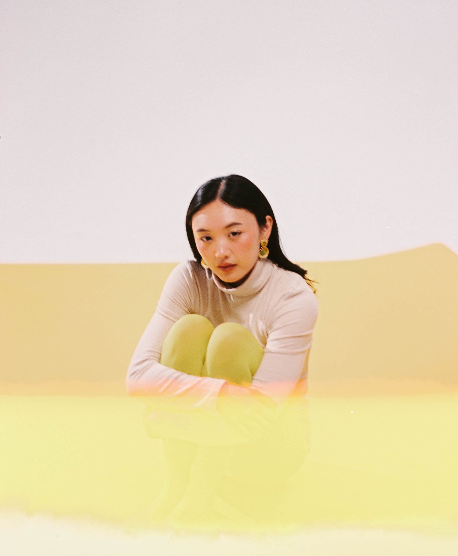 5mm film portrait in Yonkers, NY: woman in a pale pink turtleneck and lime tights on a soft yellow backdrop
