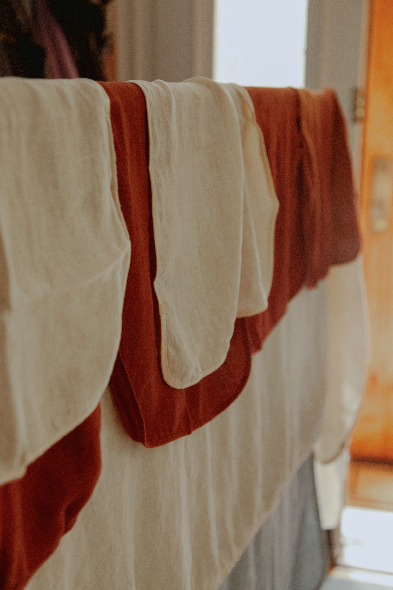 Material Kitchen linen towels in rust and cream hanging over a railing in soft natural light