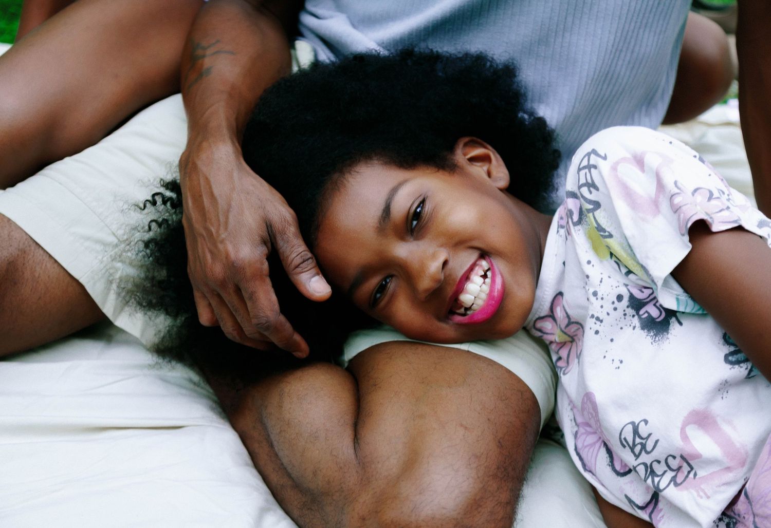 Girl laughing as she rests her head on her dad's arm during a relaxed at-home family session