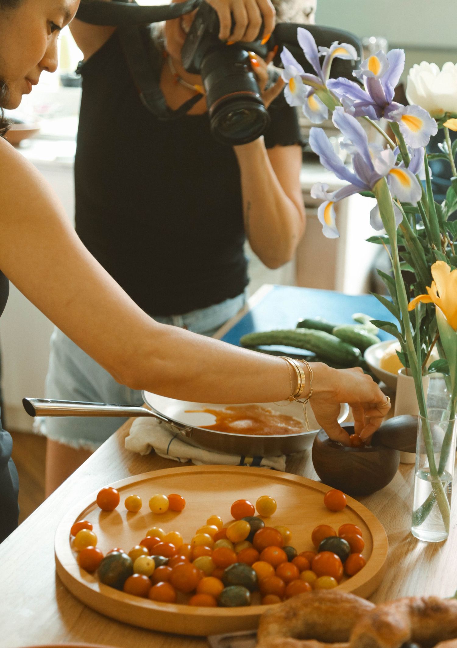 Behind the scenes: photographer capturing a cook plating cherry tomatoes on a wooden platter