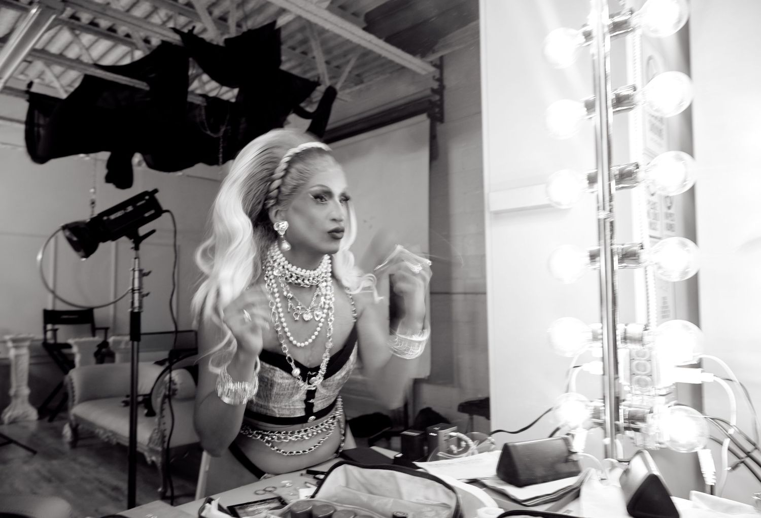 ehind the scenes black and white photo of a drag queen getting ready at a lit vanity mirror