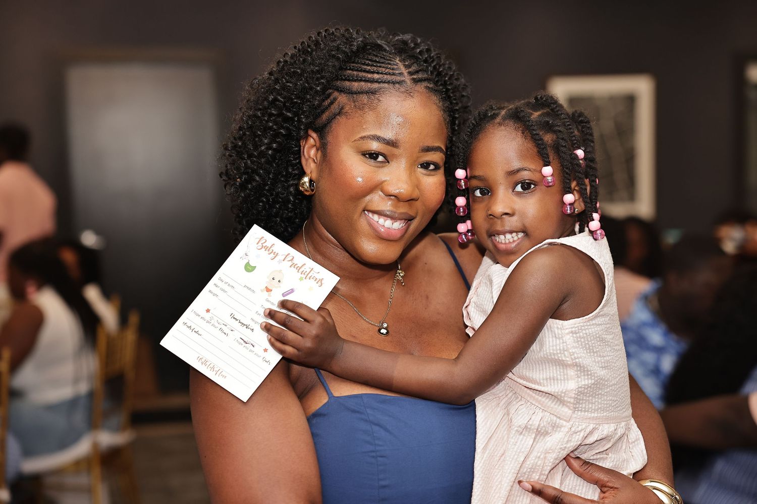 Smiling mother holding her young daughter during an indoor family celebration.