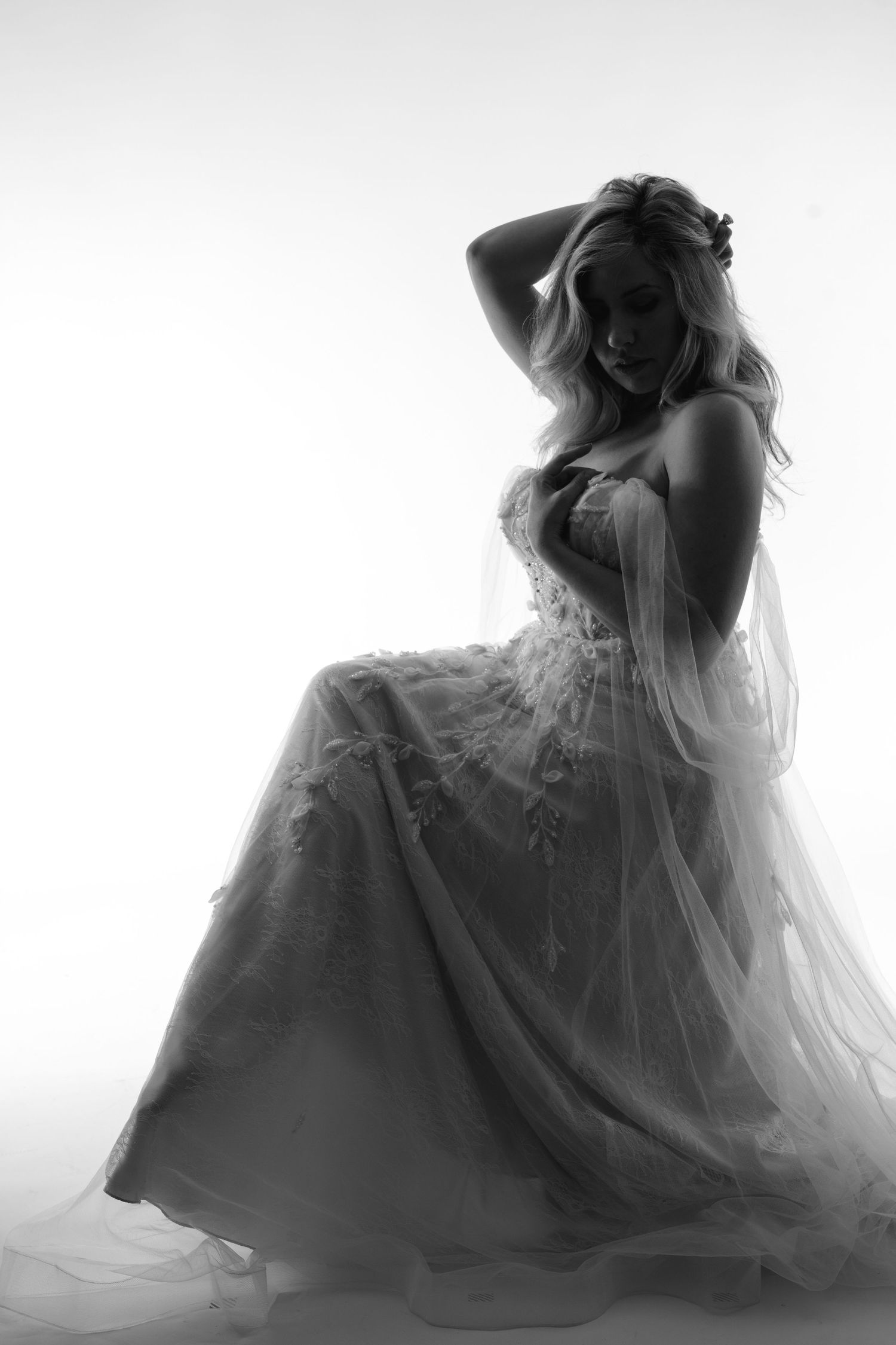 Black and white silhouette of a blonde woman in a lace wedding gown posing gracefully.