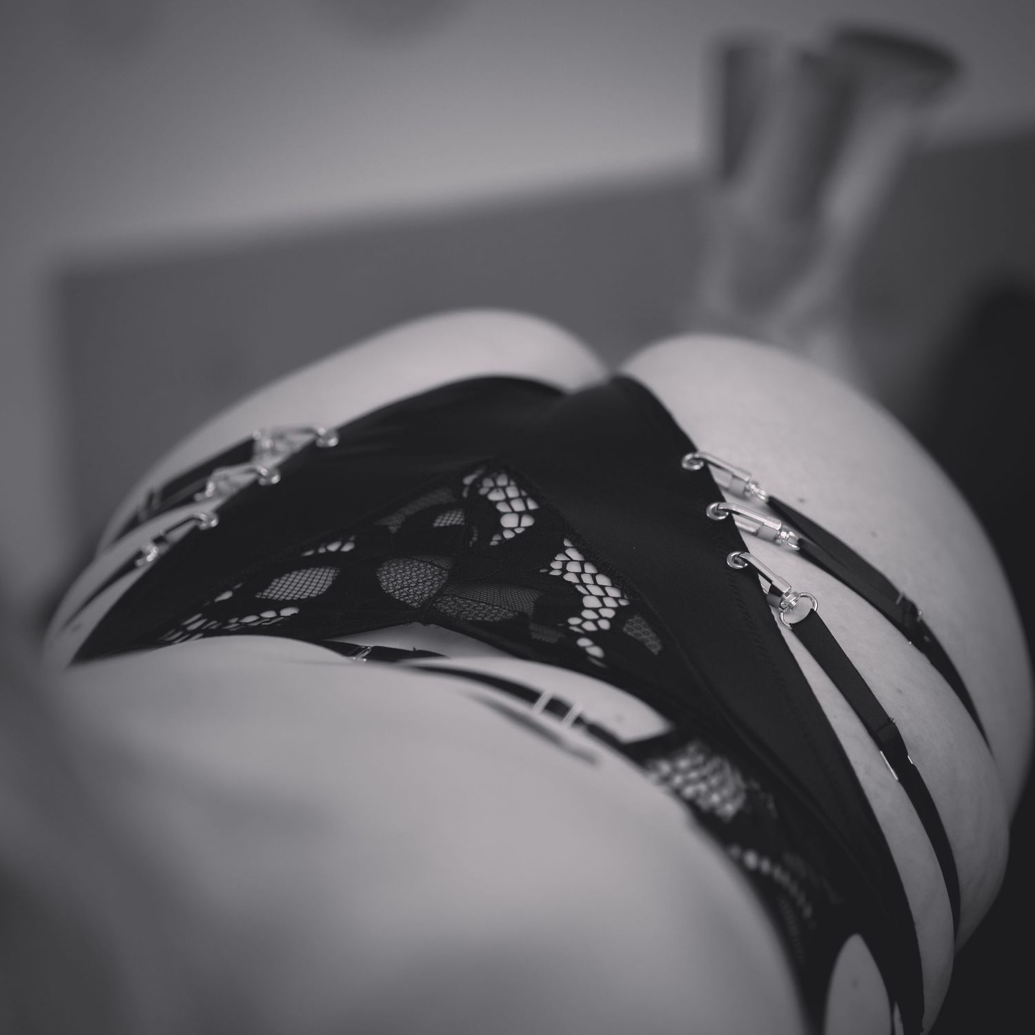 Black and white close-up of decorative black lace lingerie with chain details.
