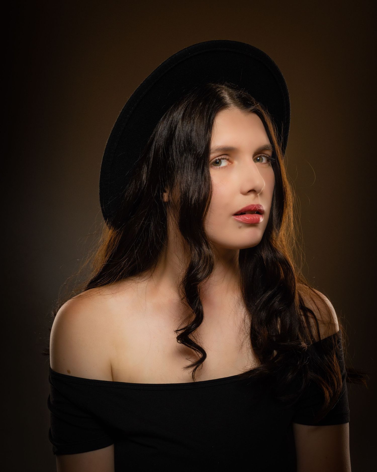Woman in black off-shoulder top and wide-brim hat with red lips.