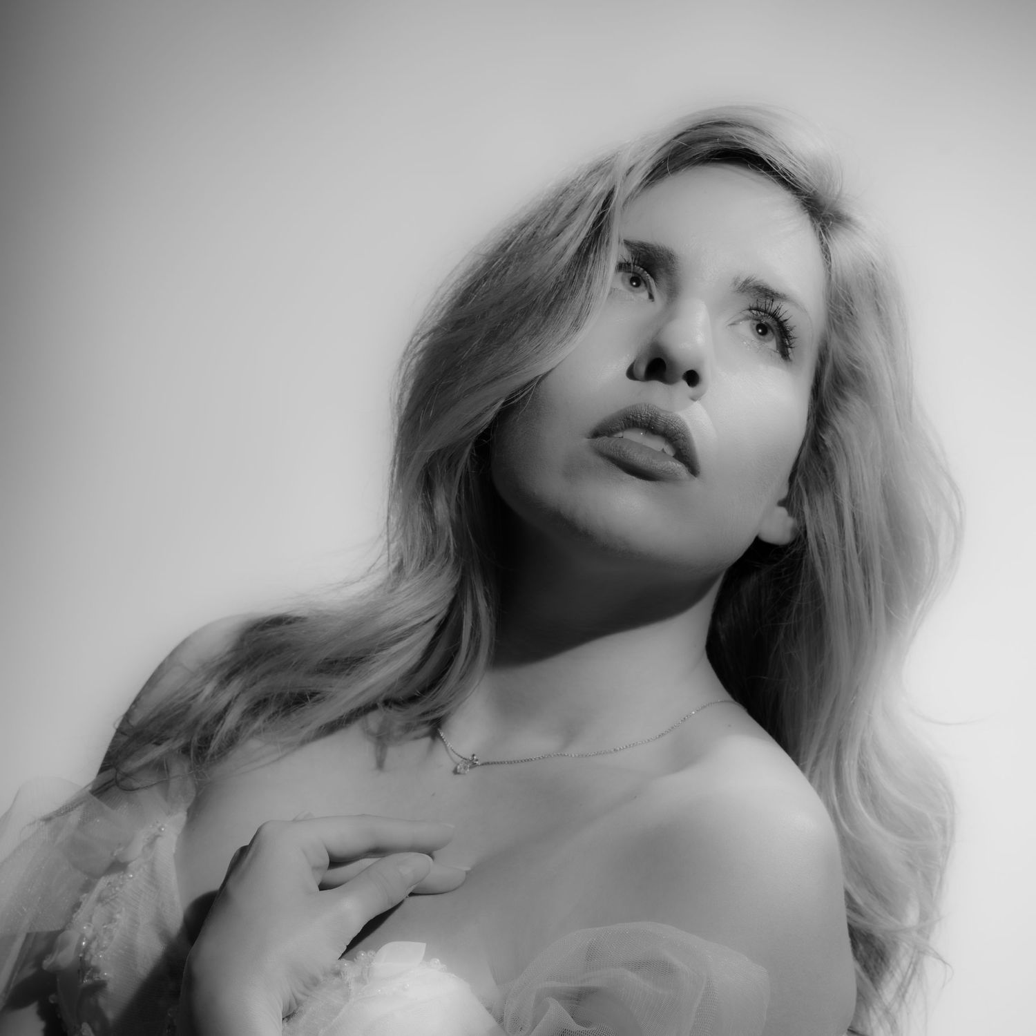 Black and white close-up portrait of a blonde woman with flowing hair and a necklace.