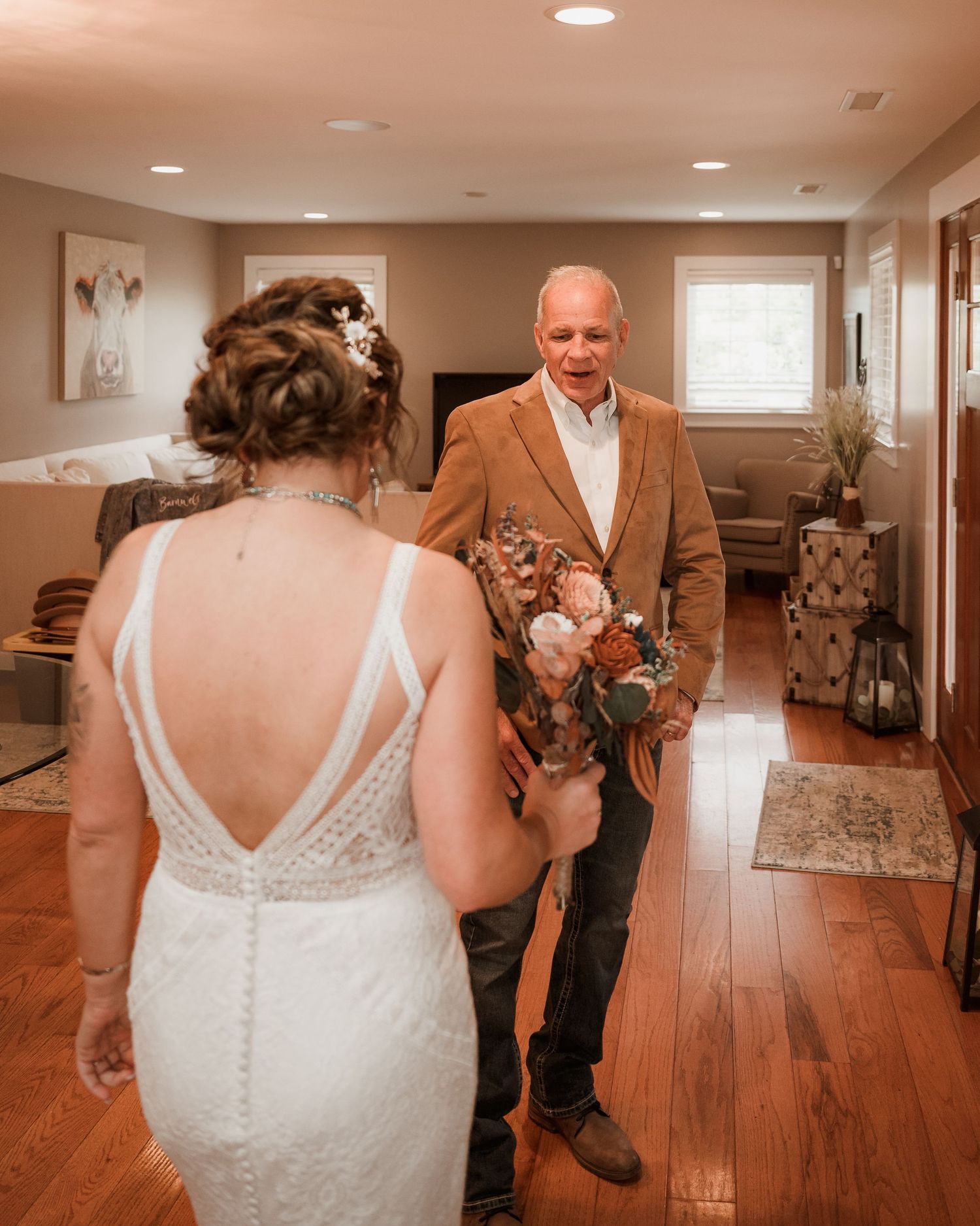 Father sees bride in wedding dress for the first time, emotional first look moment indoors.