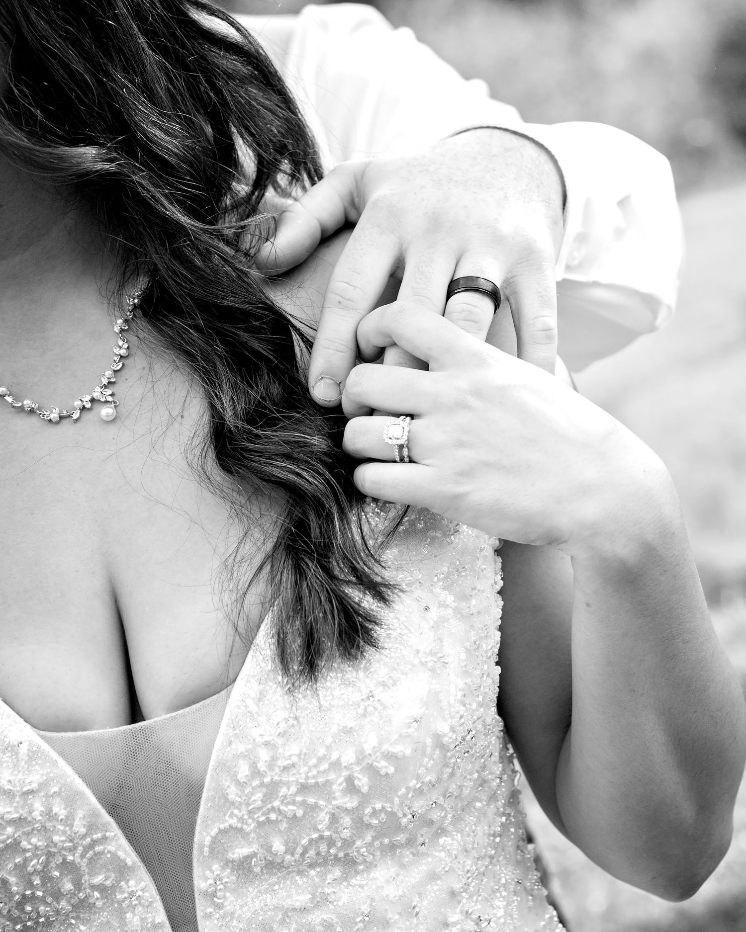 Close-up black and white photo of bride and groom's hands showing wedding rings
