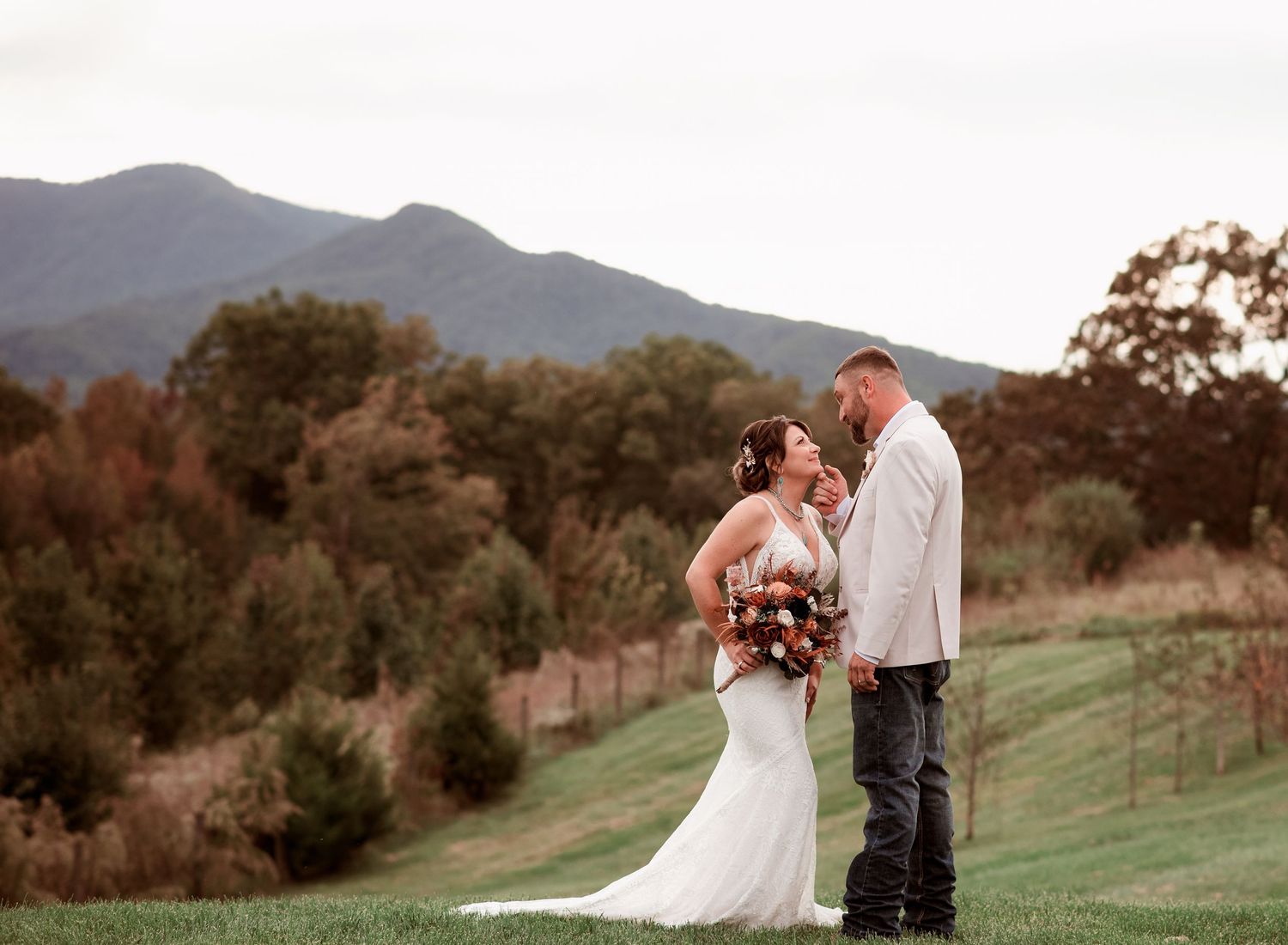 Bride and groom share romantic moment with stunning mountain backdrop during fall wedding.