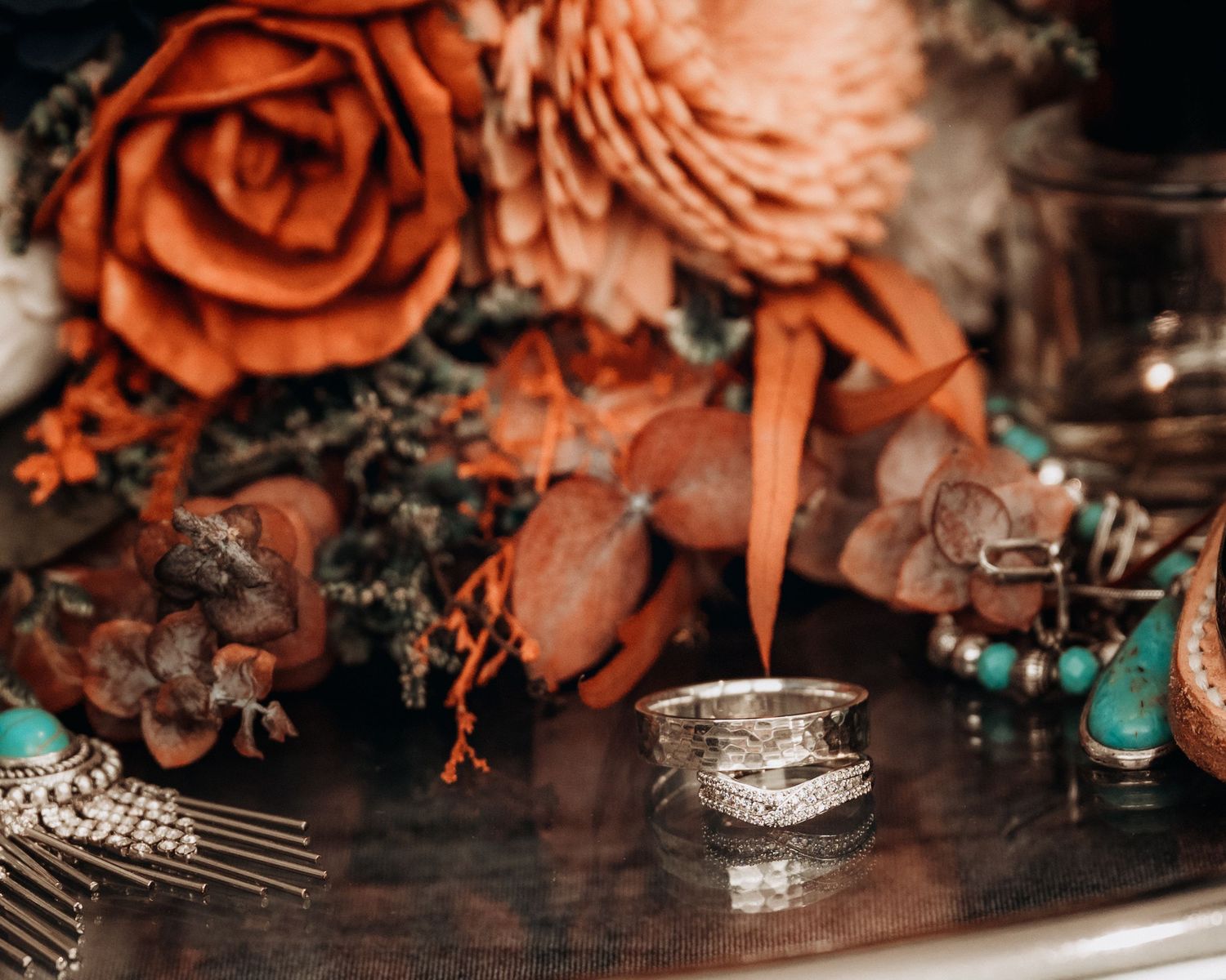 Rustic wedding flat lay featuring terracotta flowers, turquoise jewelry, and silver hair accessories.