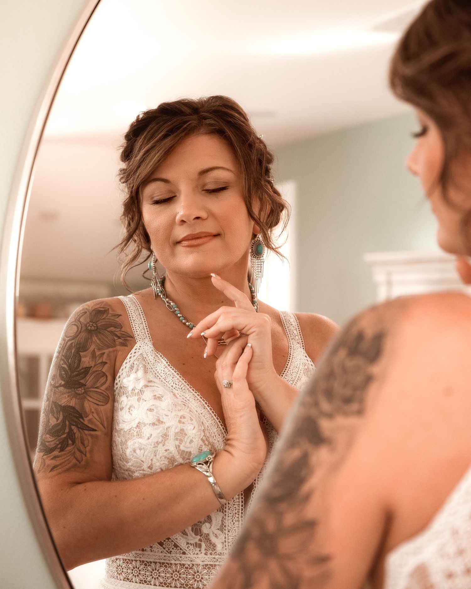 bride admires her ring in a round mirror while getting ready for her wedding.
