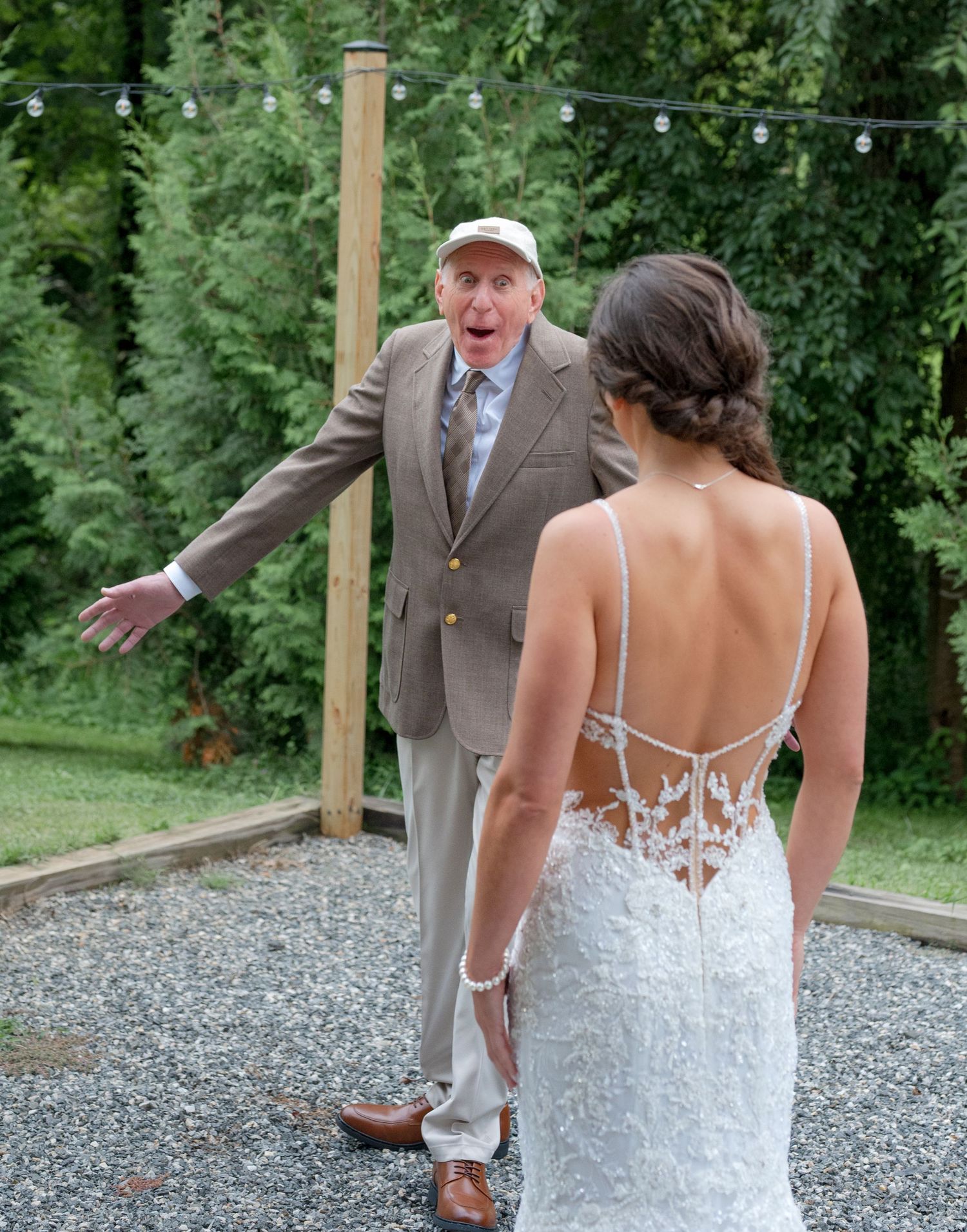 Grandfather reacts with joy and surprise seeing granddaughter in wedding dress outdoors.