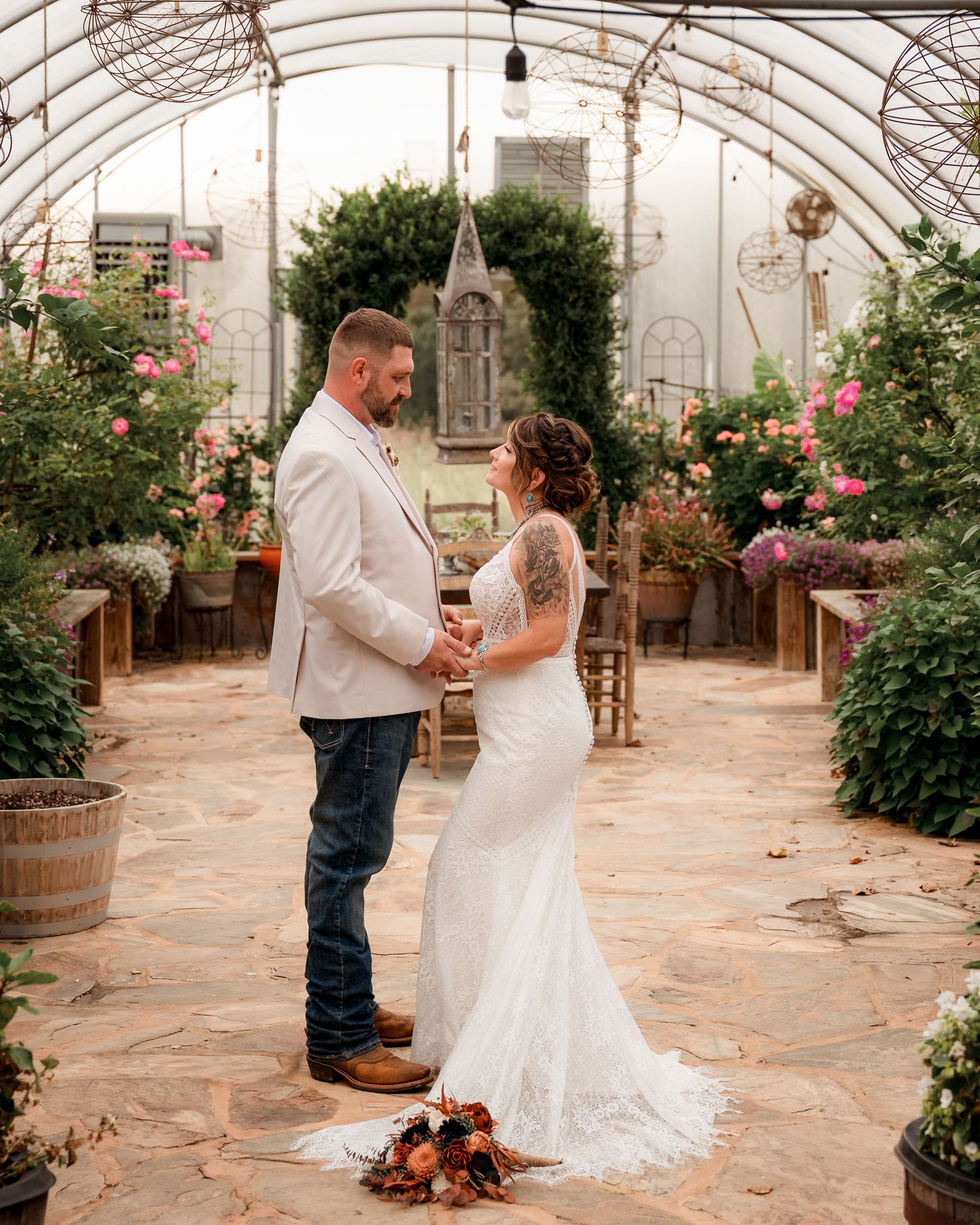 Bride and groom exchange vows in a romantic greenhouse wedding ceremony surrounded by lush flowers and greenery.