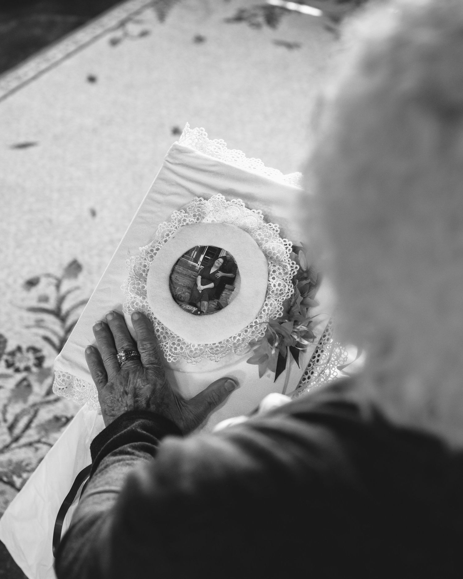 Black and white photo of elderly hands holding a framed wedding photo with lace.