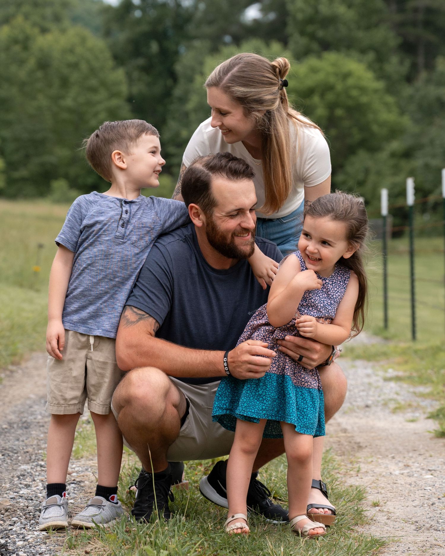 A cheerful family of four shares a fun candid moment together on a gravel path in nature.