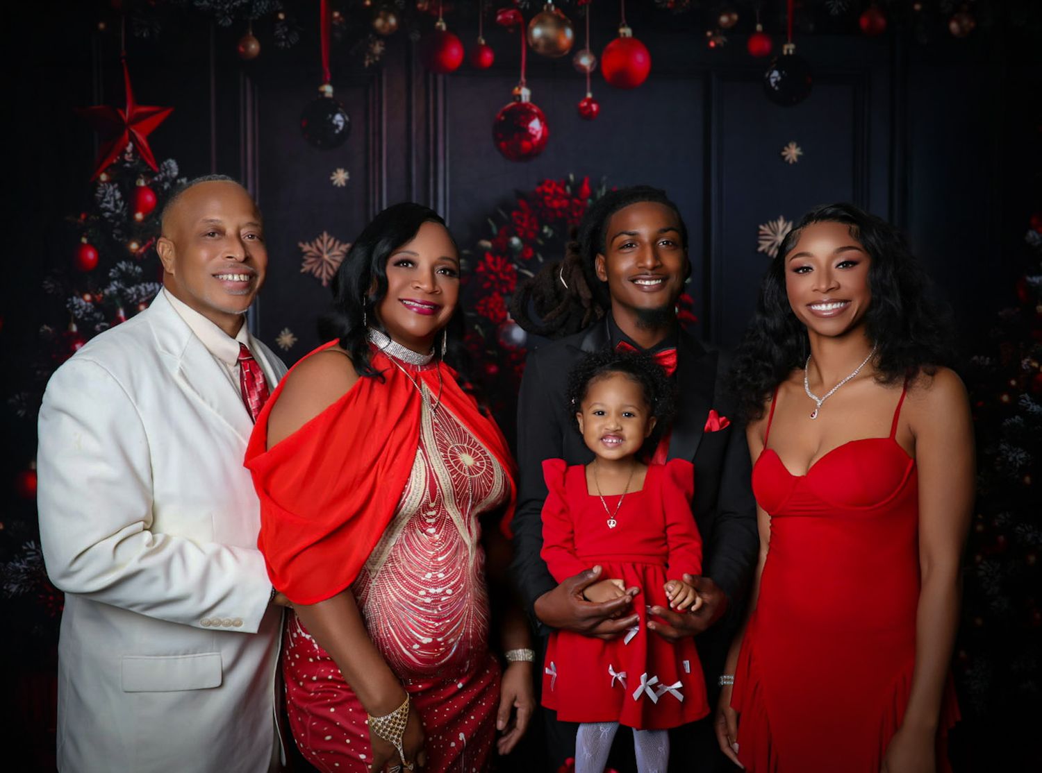 Family of five in red and white outfits posing before festive Christmas decorations.