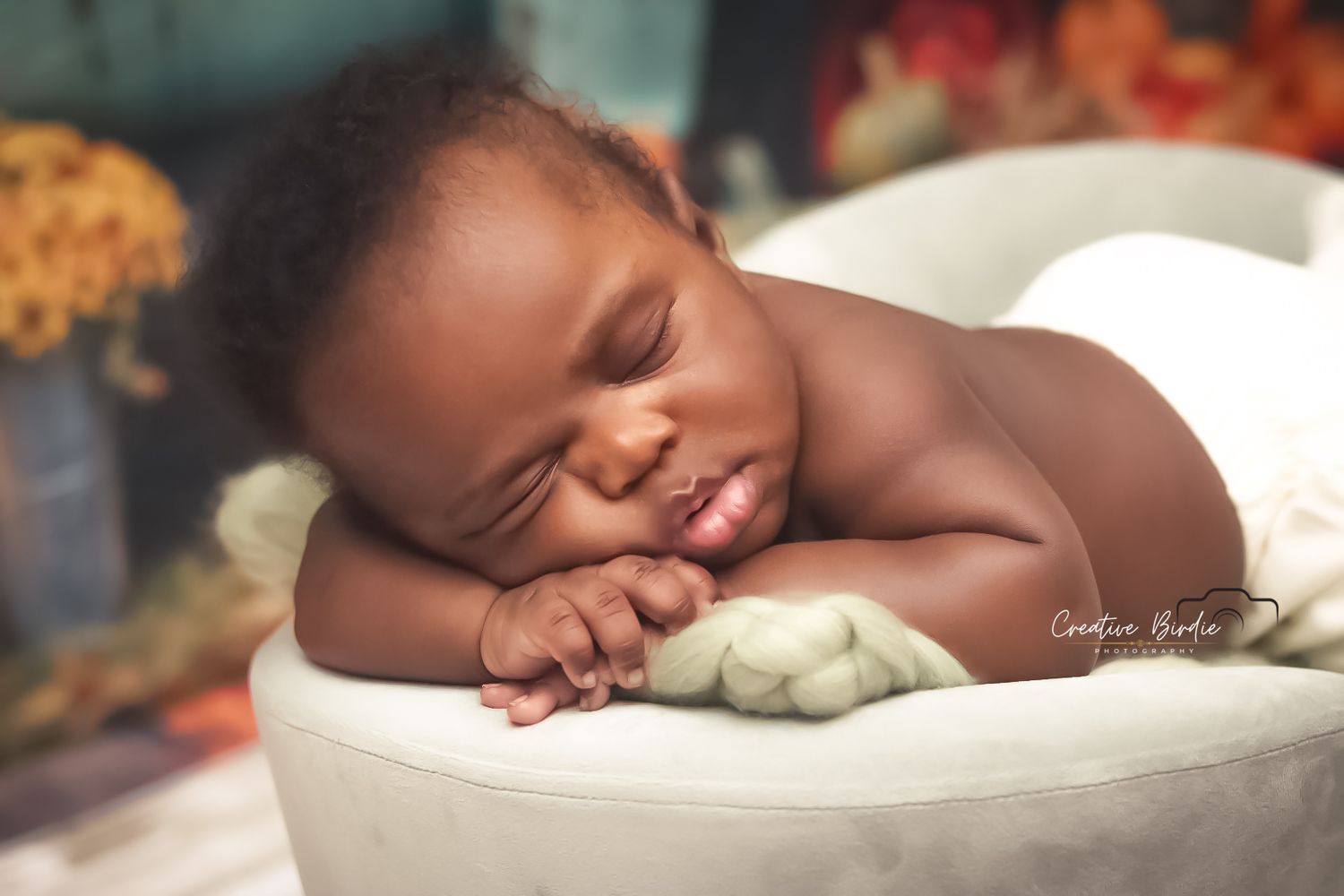 Smiling sleeping newborn baby rests peacefully on soft white surface in professional studio portrait.