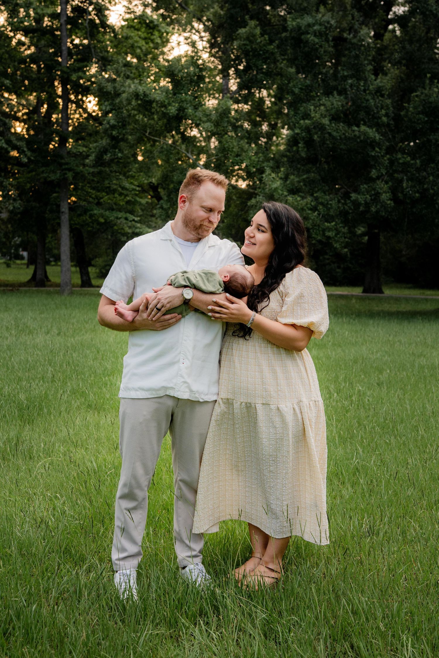Couple sharing an intimate moment in a grassy field at sunset while posing for pictures.