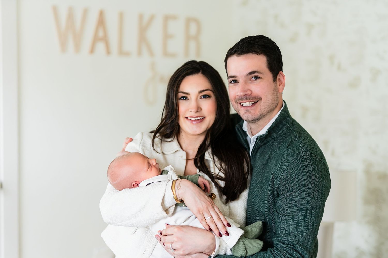 Family portrait with newborn baby in front of wall with text.