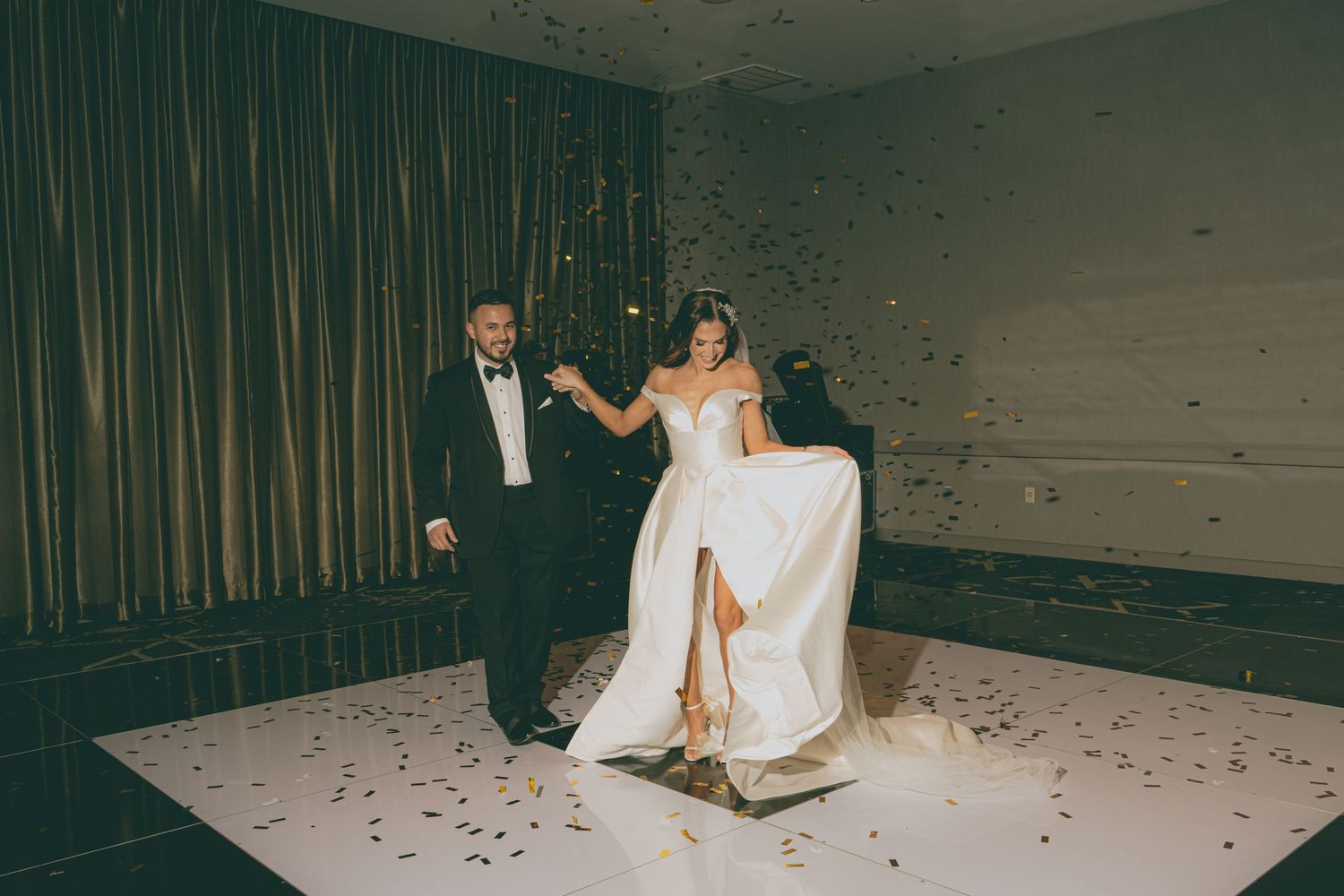 A couple dances on a white floor with confetti during their wedding reception.