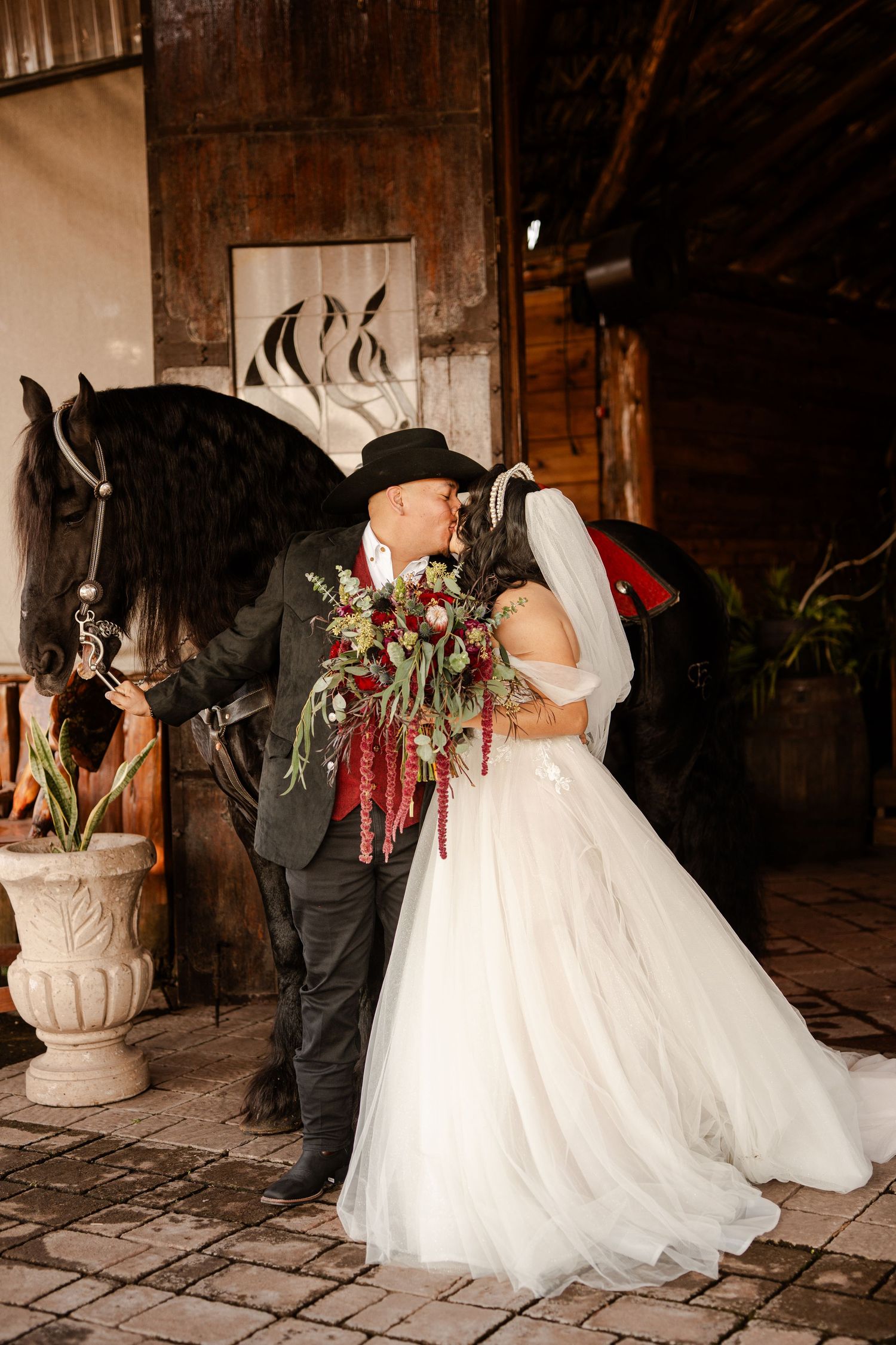 A romantic wedding moment in a rustic barn with a beautiful white horse in the background.