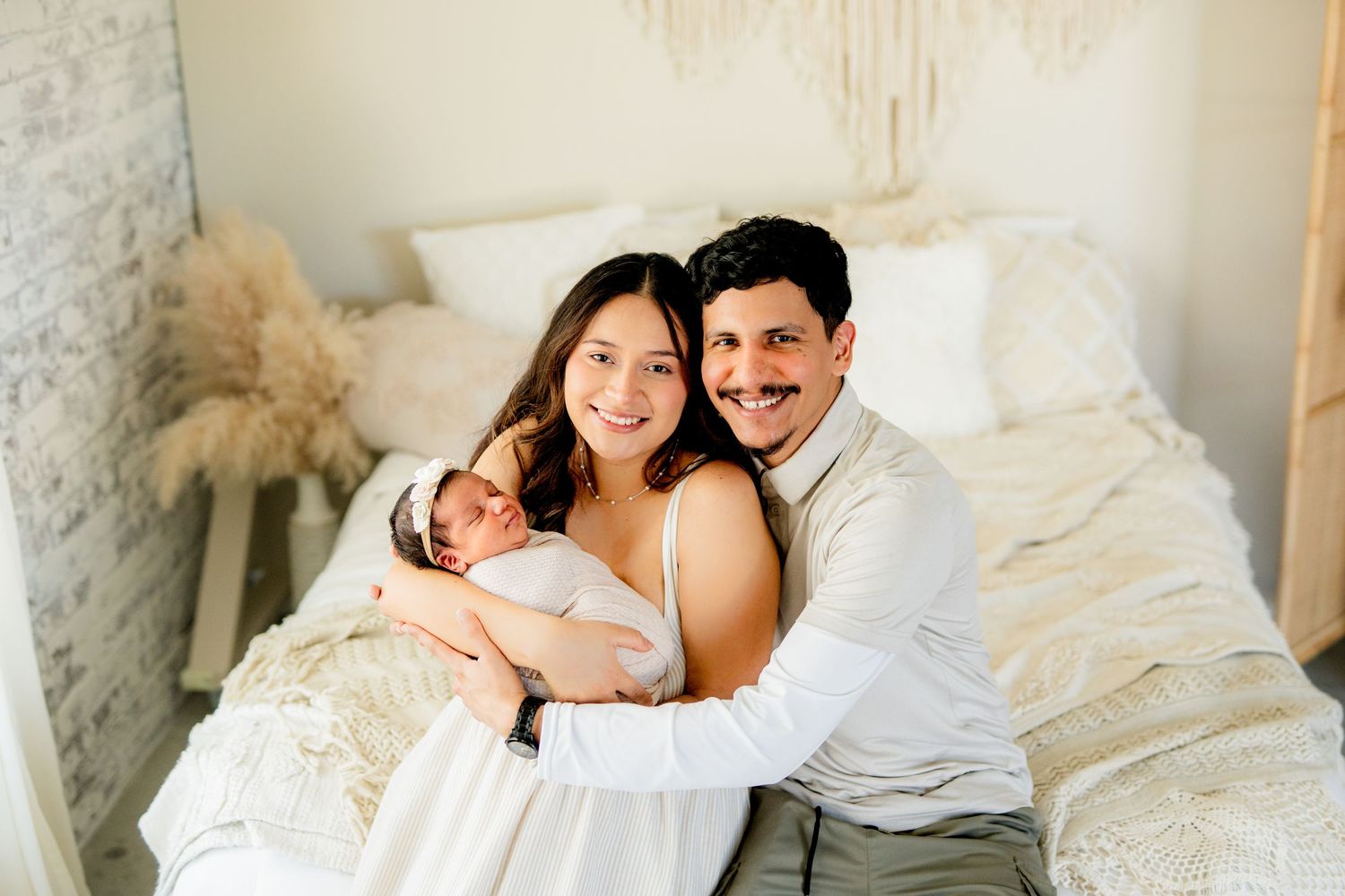 Happy family snuggle together on white bedding in a cozy bedroom setting.